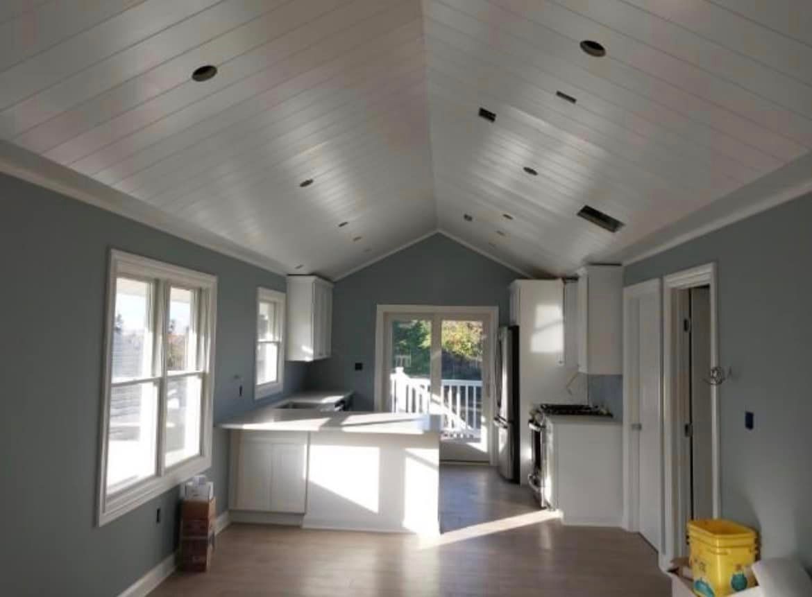 A kitchen with a vaulted ceiling and white cabinets