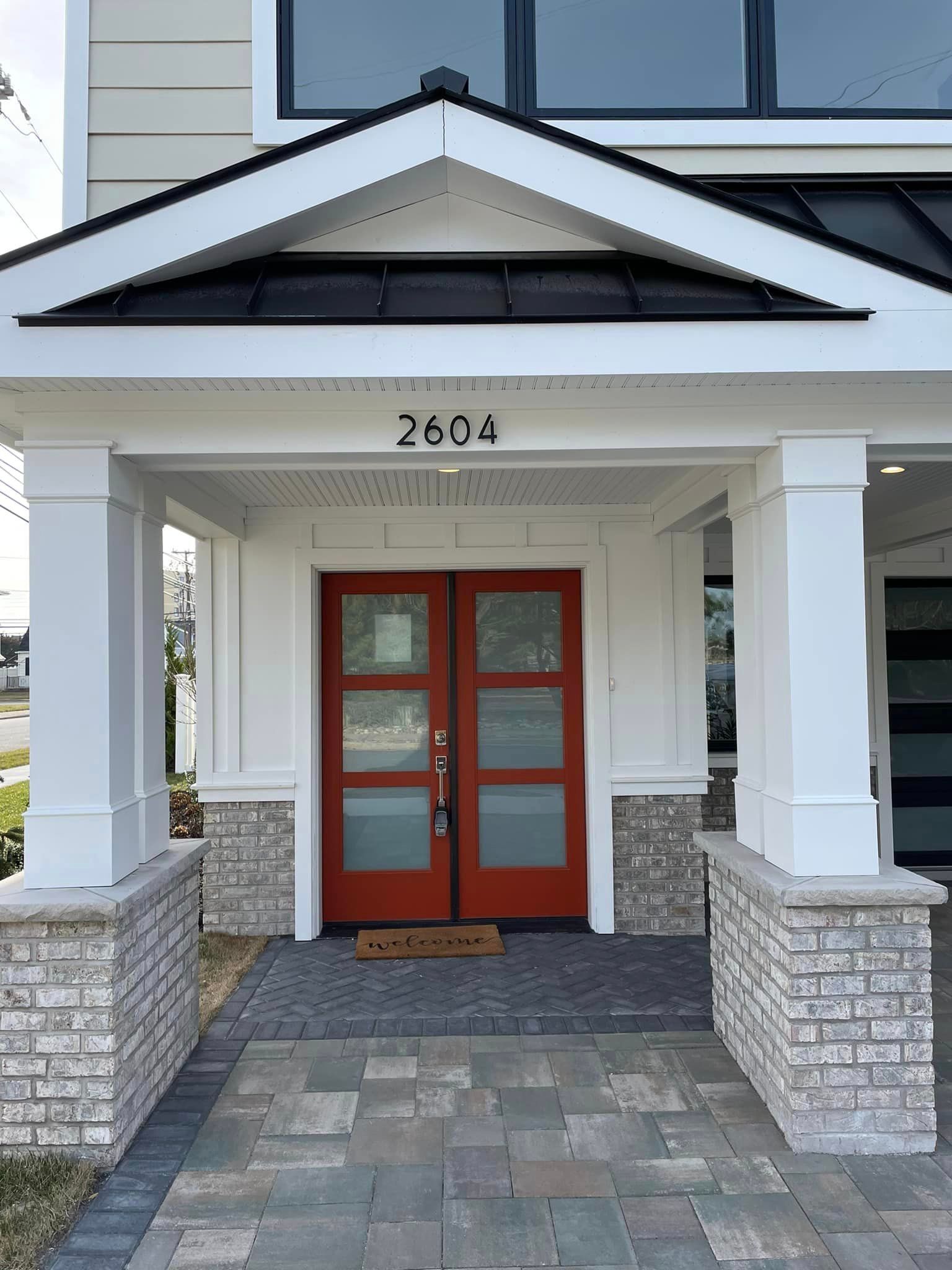 A white house with a red door and a porch.