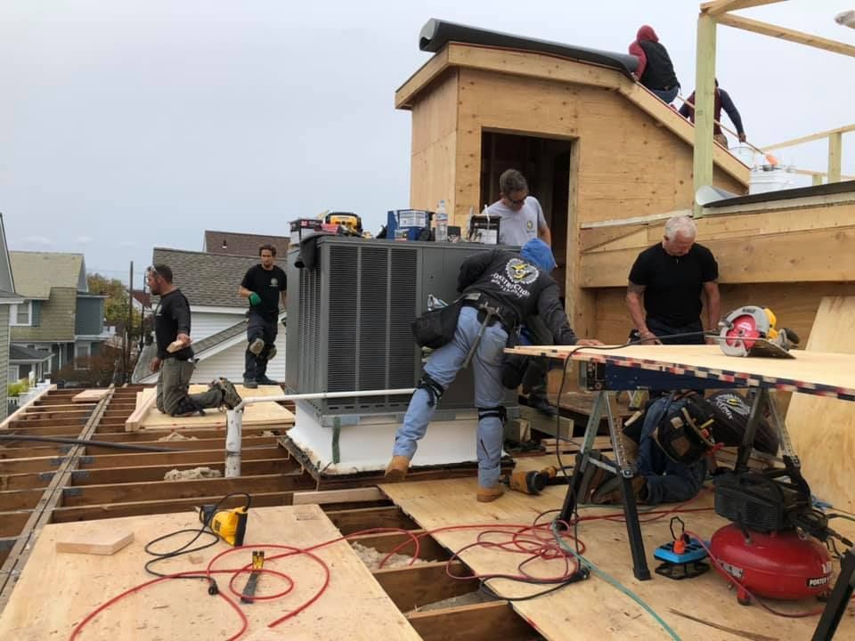 A group of men are working on the roof of a house.