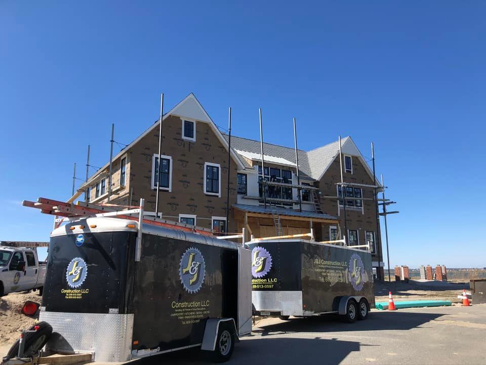 Two trailers are parked in front of a building under construction.