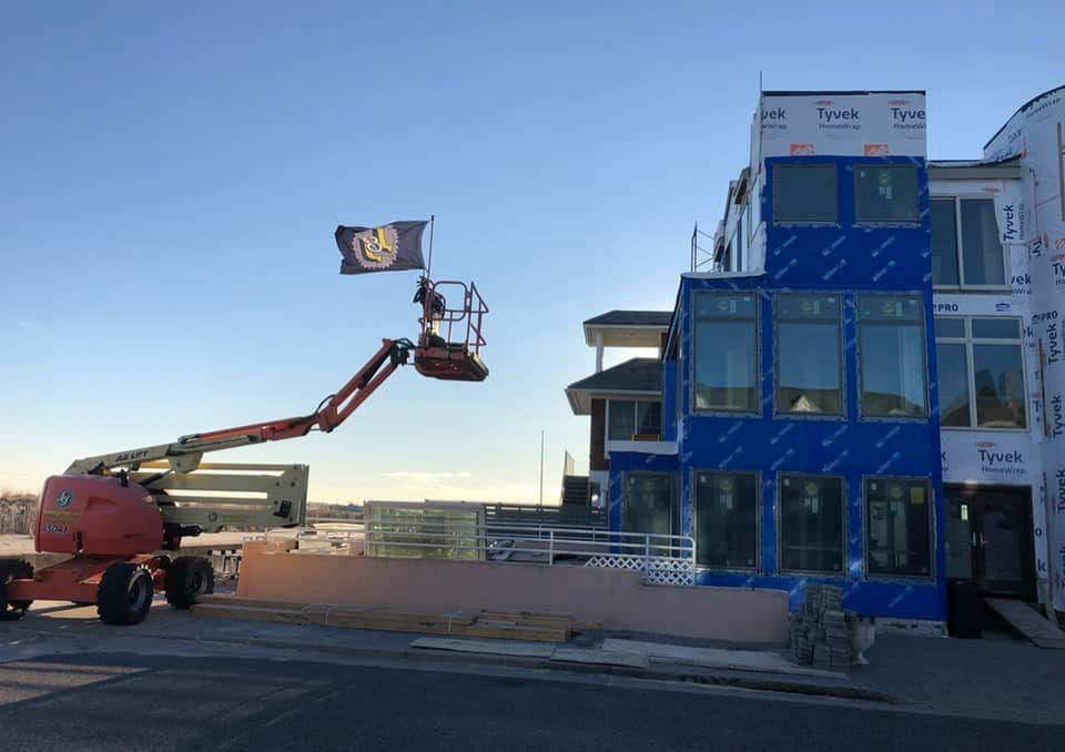 A crane is lifting a flag in front of a building under construction.