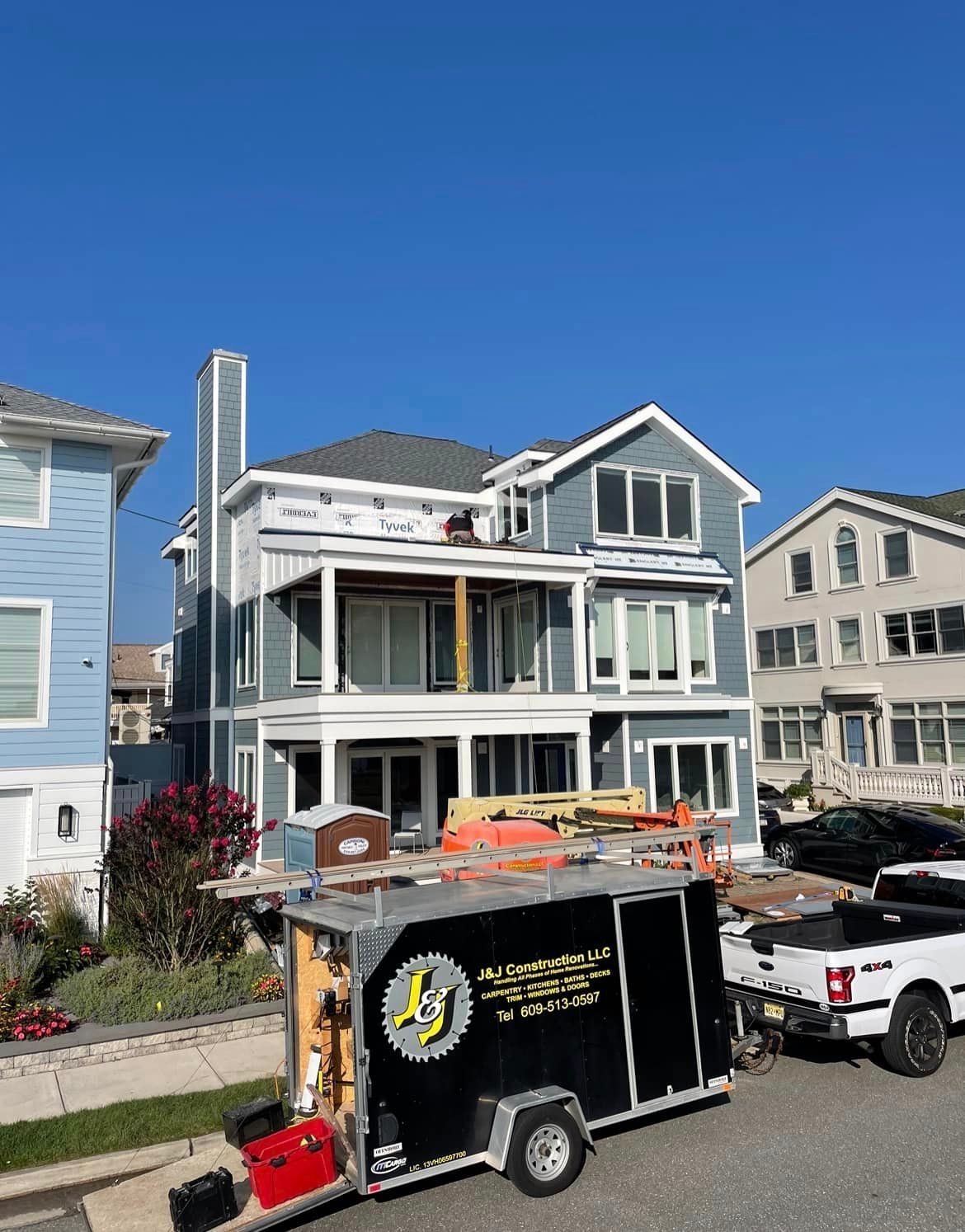 A black trailer is parked in front of a large house.