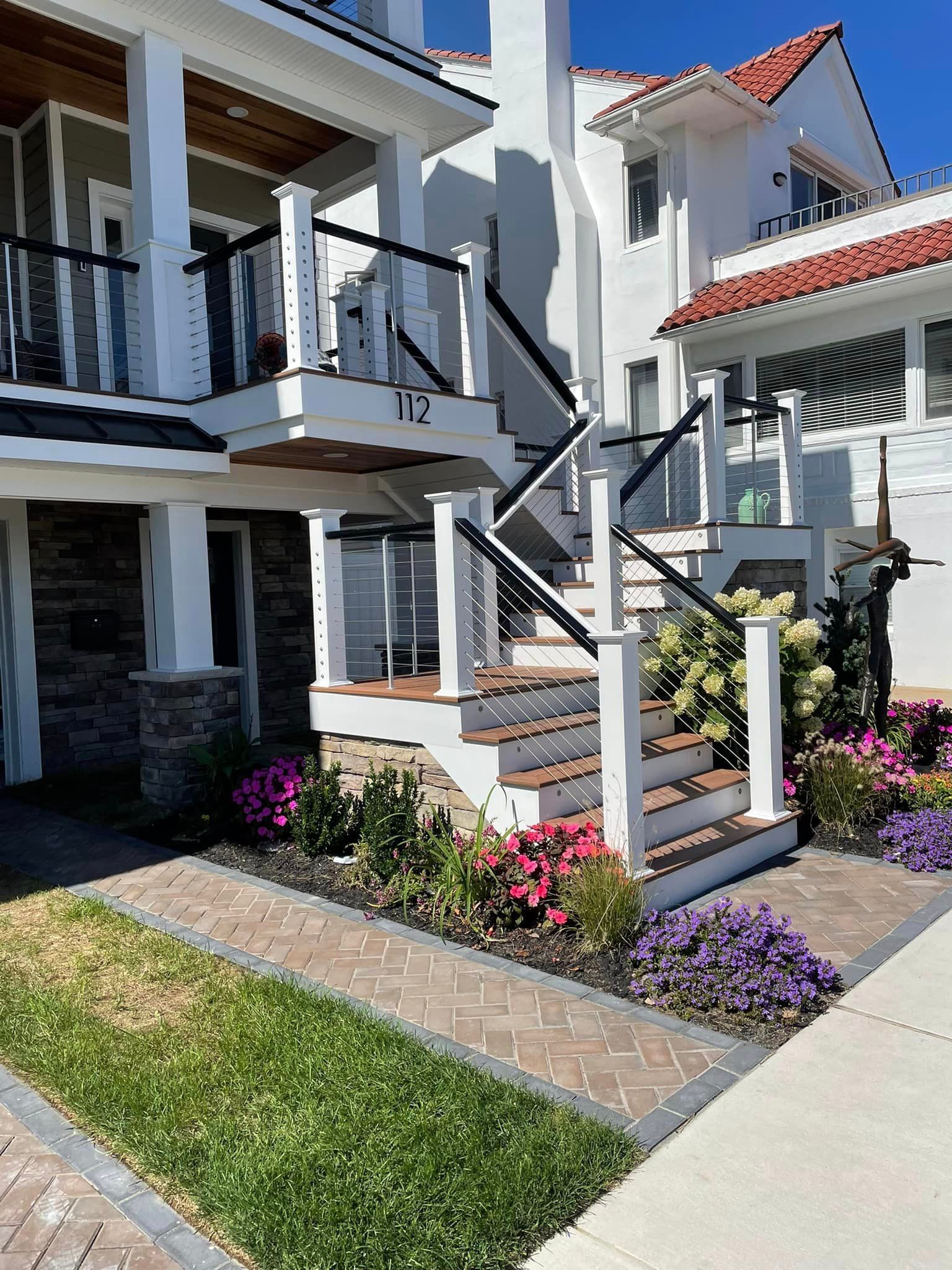 A white house with stairs leading up to the second floor.
