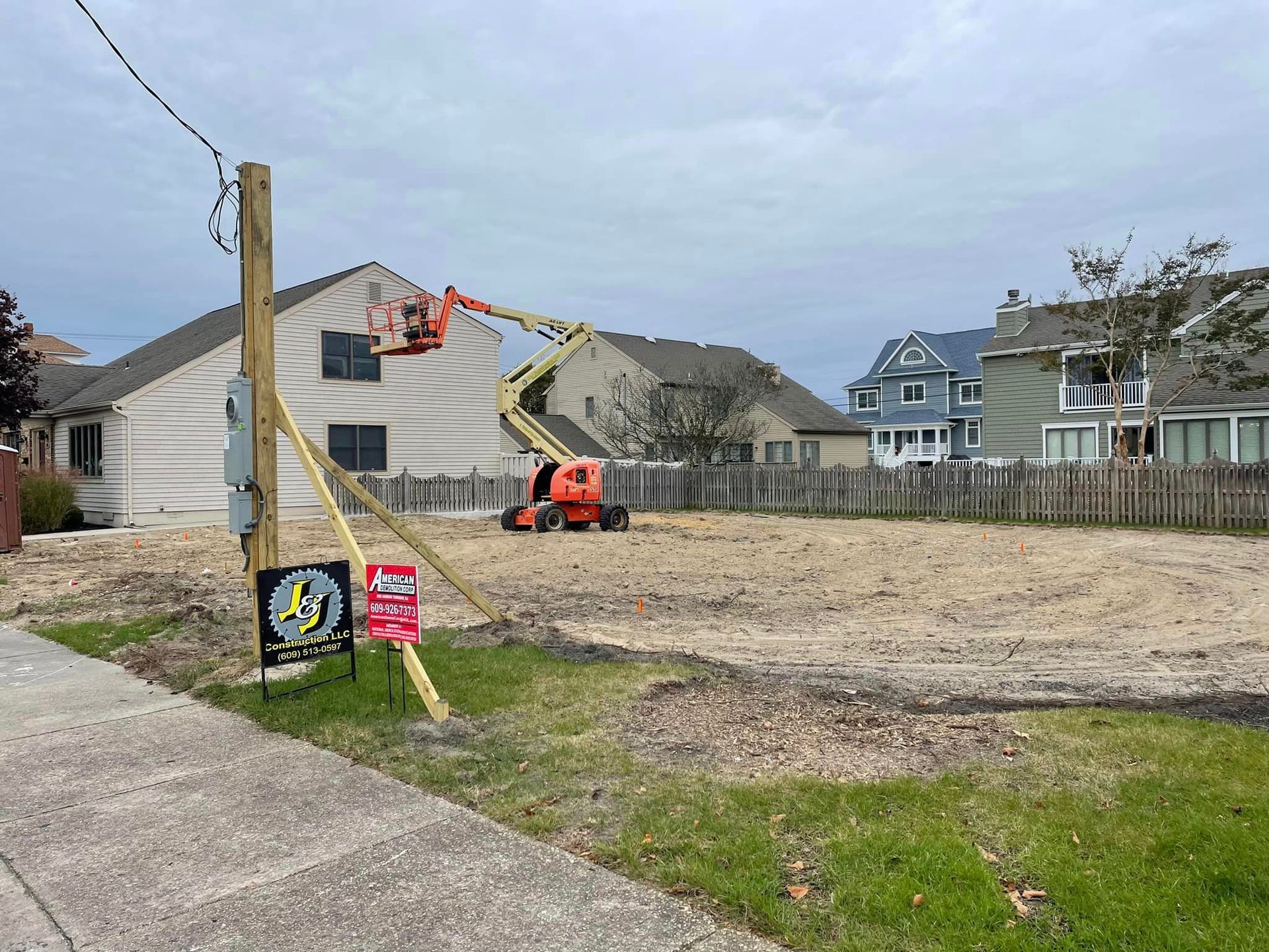 A construction site with a lot of dirt and a house in the background.