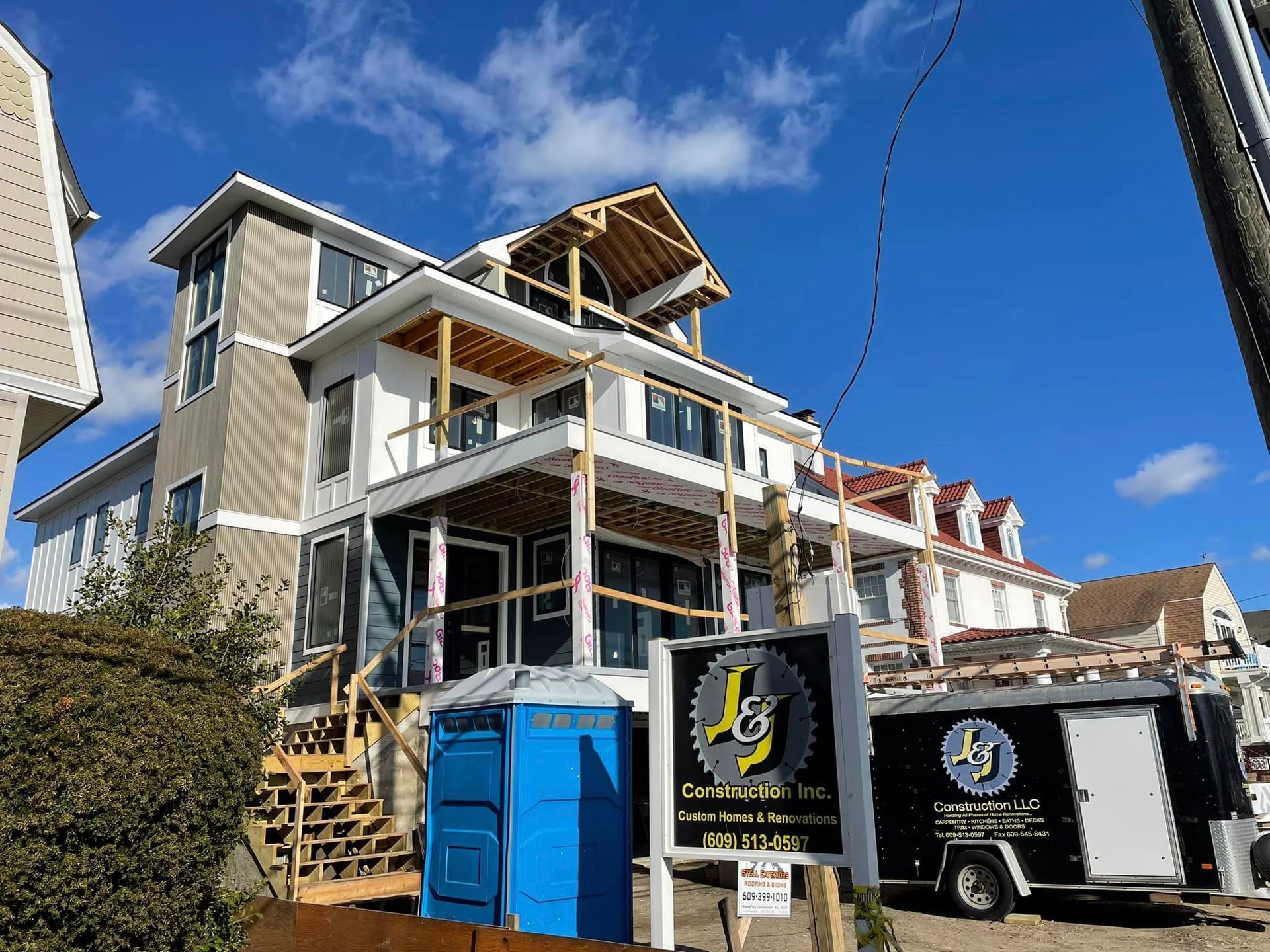 A large house under construction with a blue portable toilet in front of it.