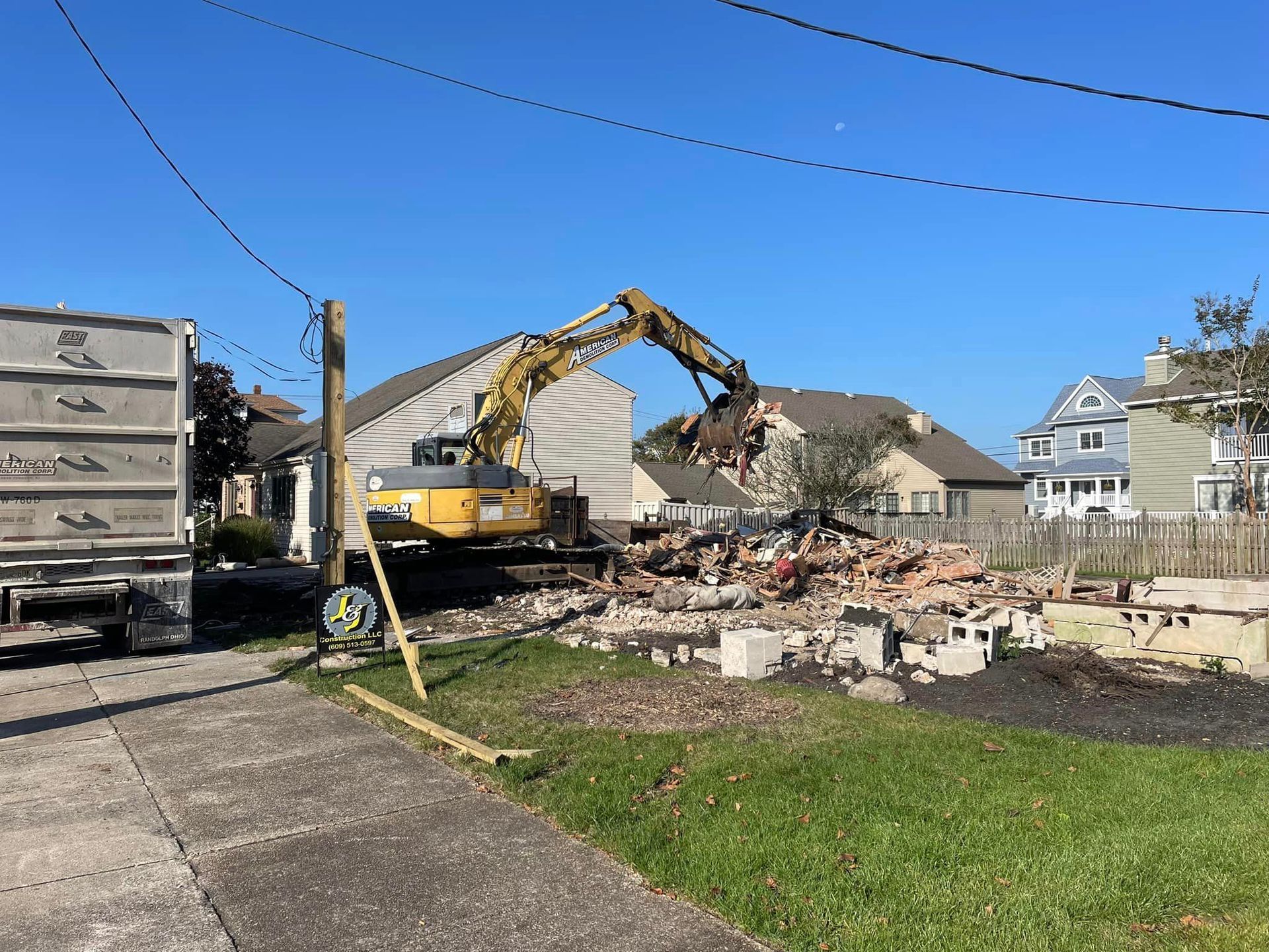 A large yellow excavator is demolishing a house.