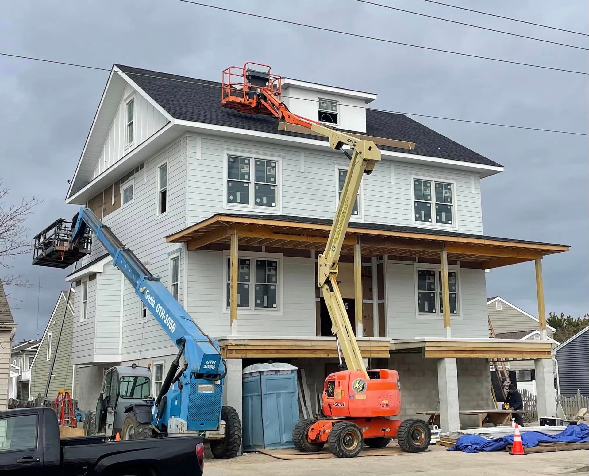 A large white house is being built with a crane on the roof.