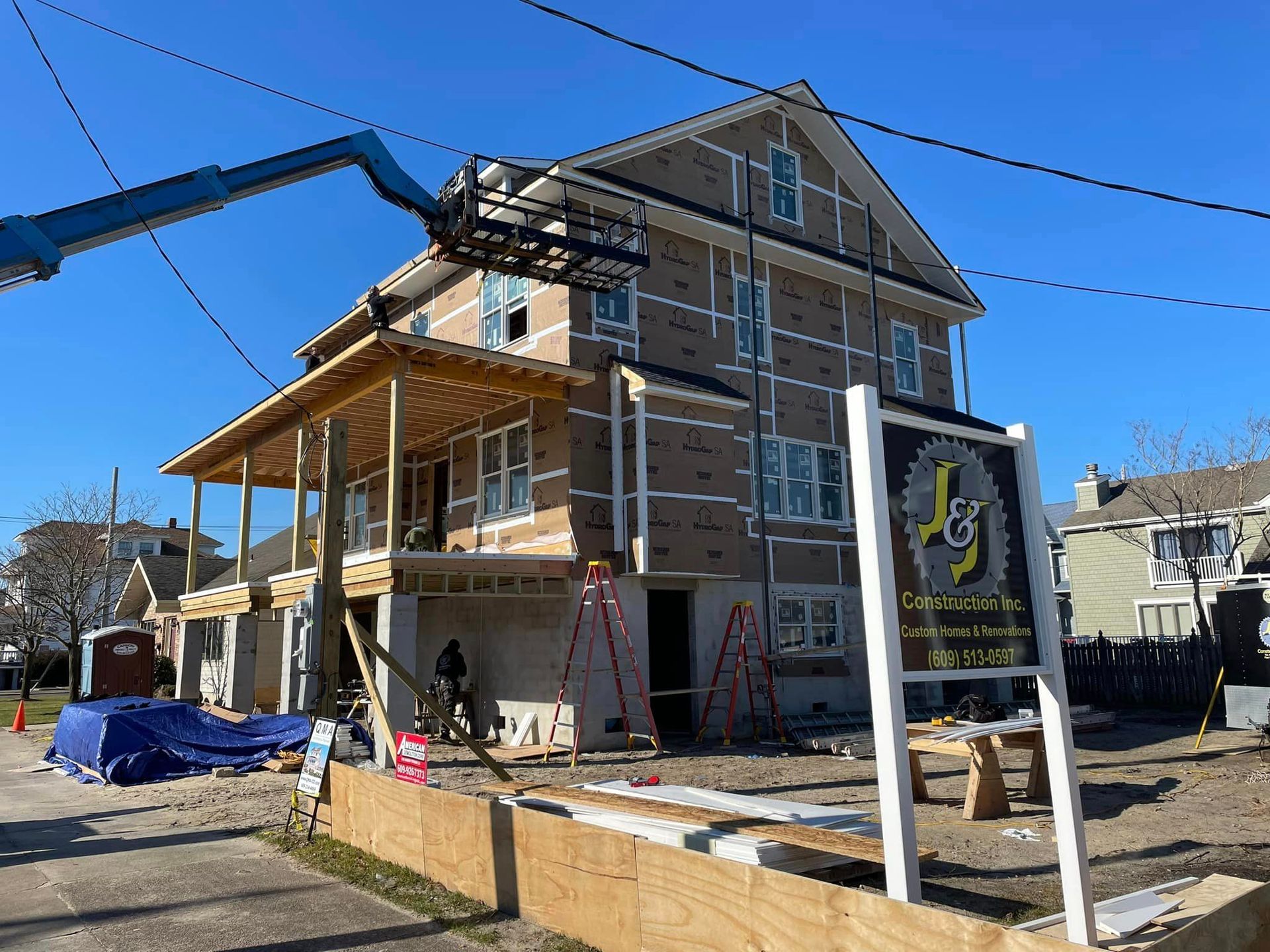 A large house is being built with a sign in front of it.
