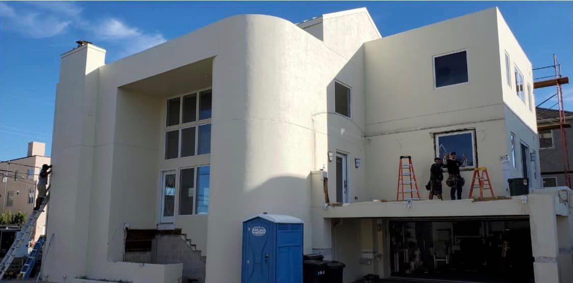 A large white building with a blue portable toilet in front of it