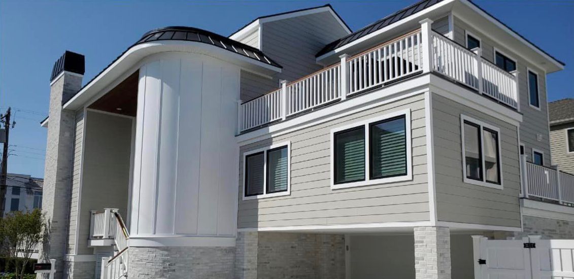 A large white house with a balcony and a blue sky in the background.