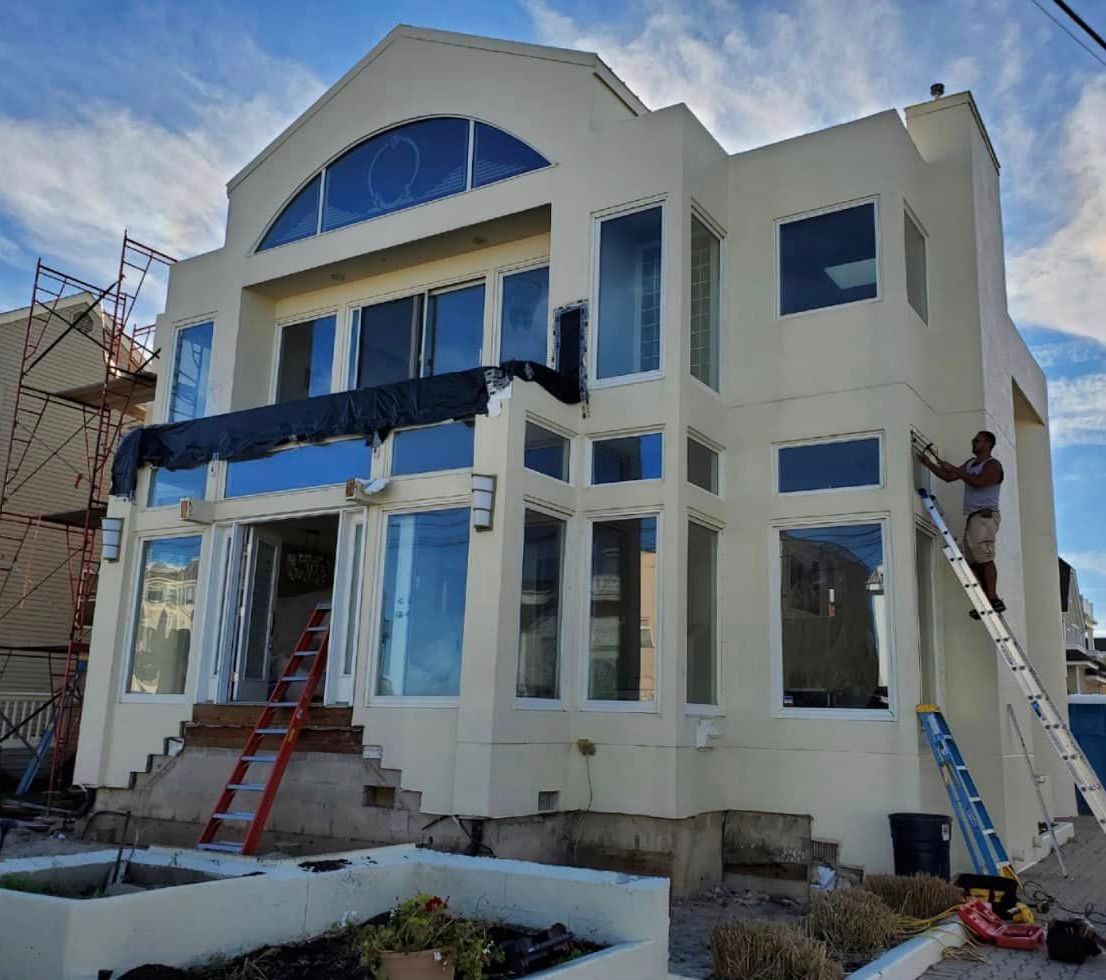 A man on a ladder is painting a large white house