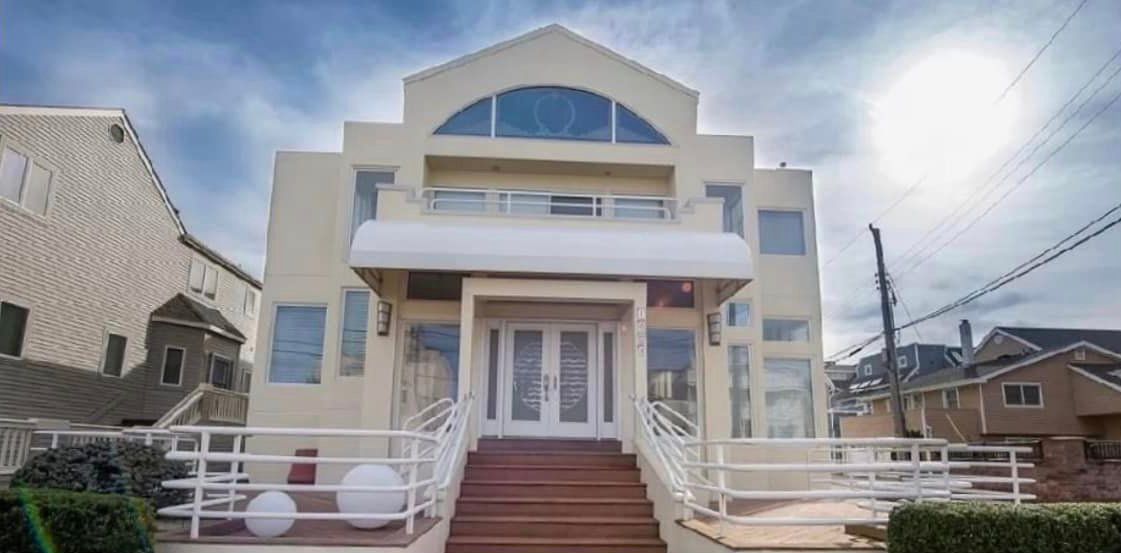 A large white house with stairs leading up to the front door.