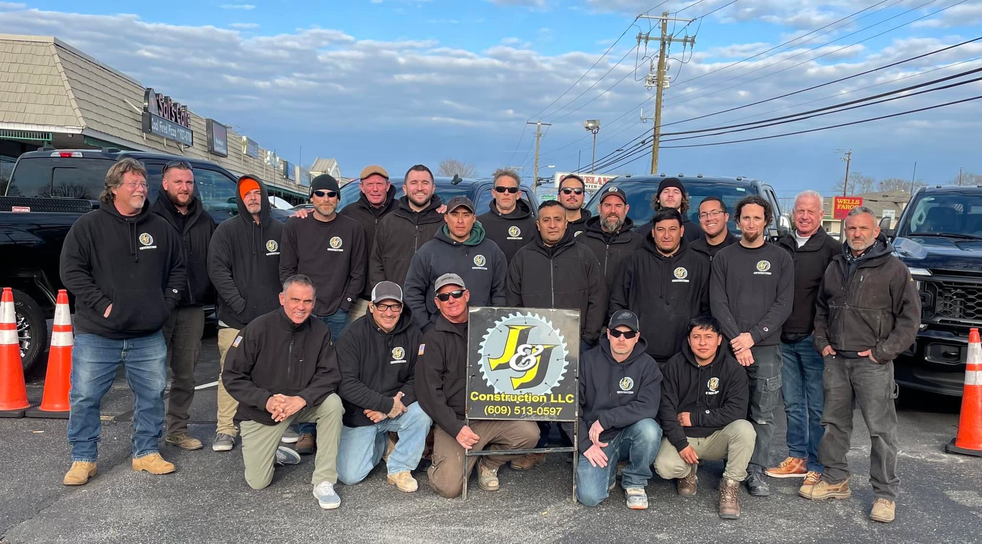 A group of men are posing for a picture in front of trucks.