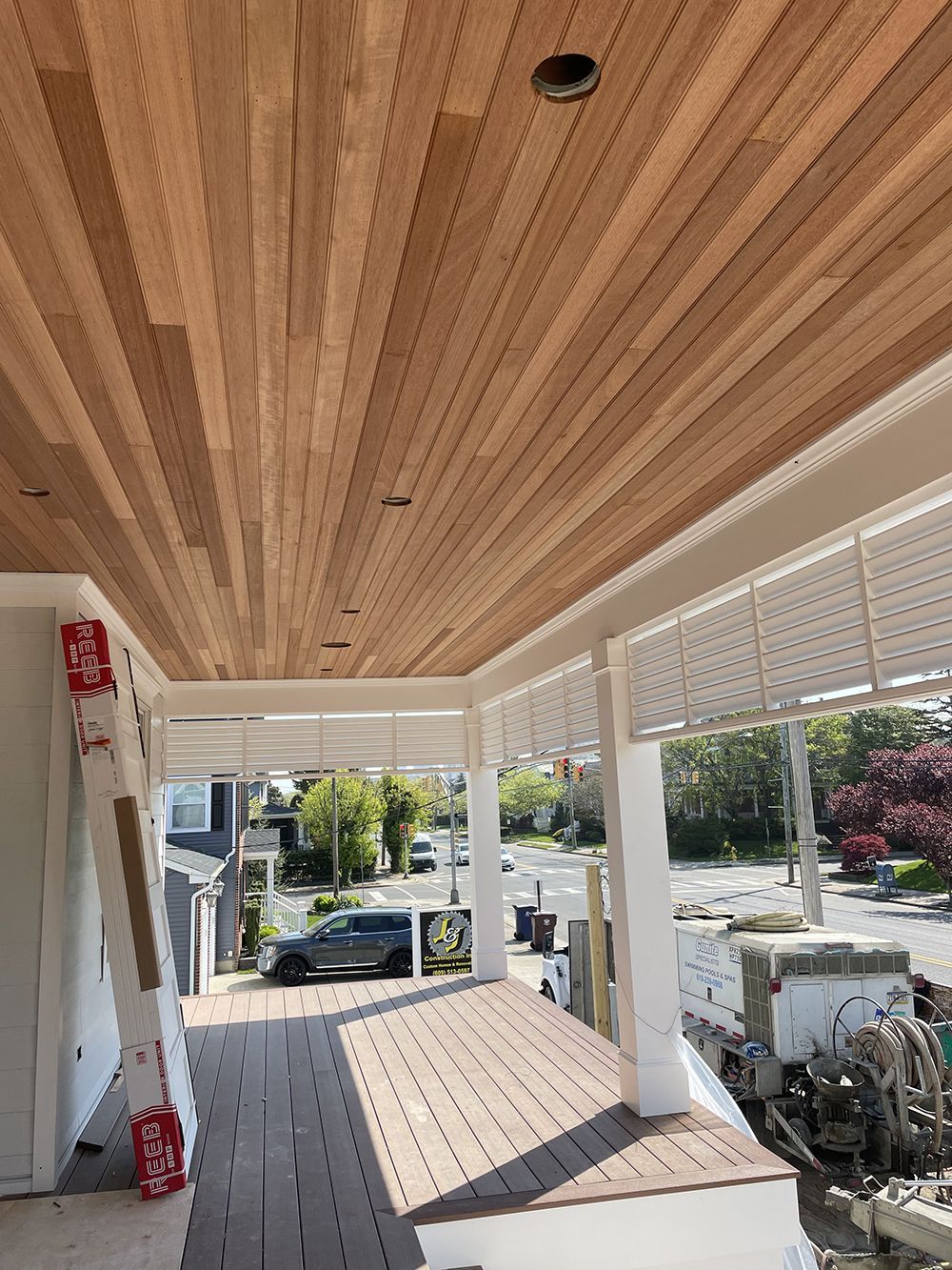 A porch with a wooden ceiling and a ladder.