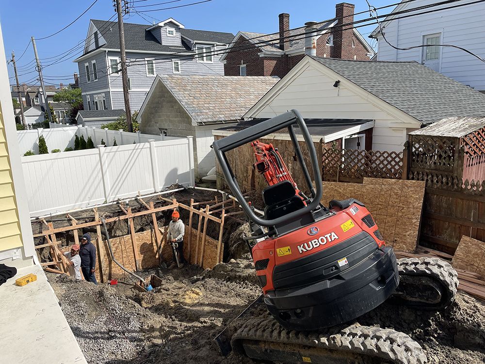 A kubota excavator is working on a construction site in front of a house.