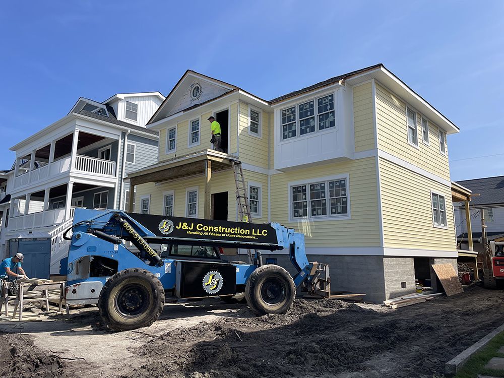 A large house is being built with a forklift in front of it.