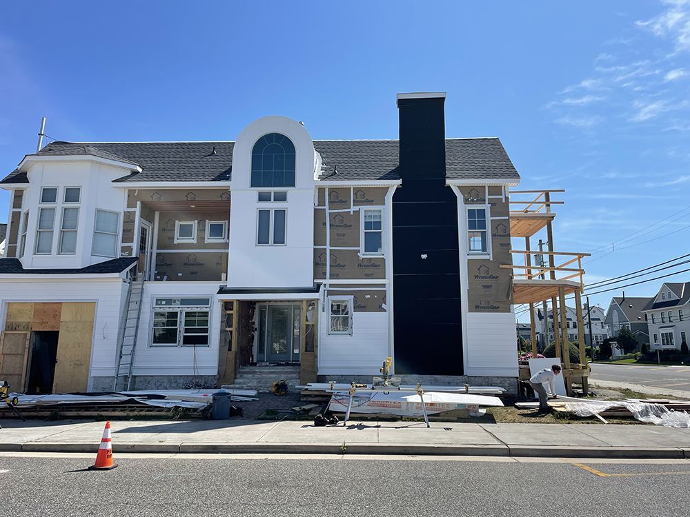 A large white house with a black chimney is being built on the side of the road.