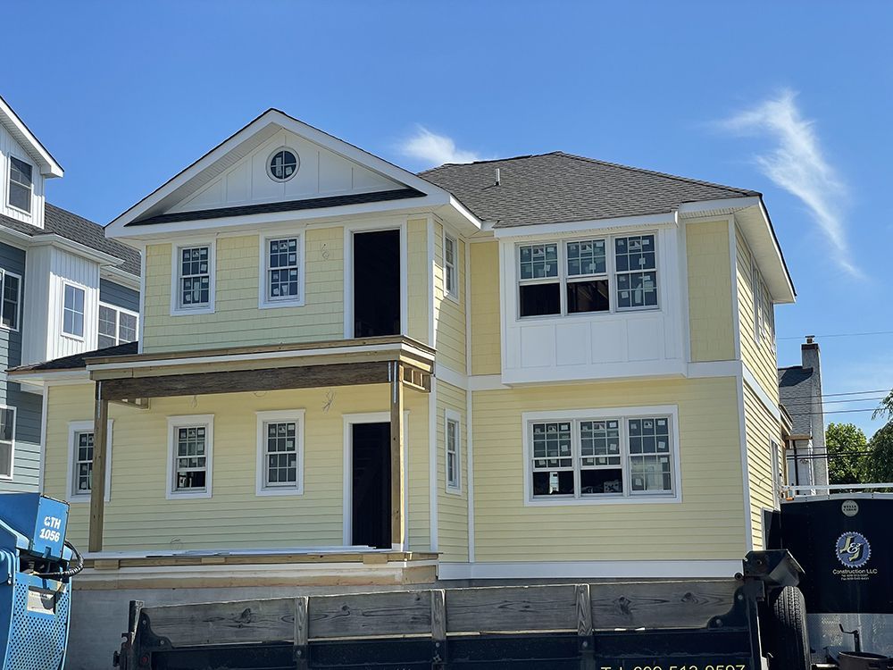 A large yellow house with white trim is being built.