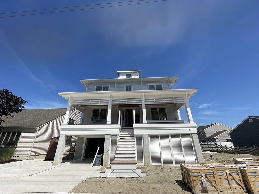 A large white house with a blue sky in the background is under construction.