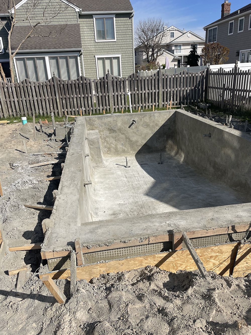 A swimming pool is being built in the backyard of a house.