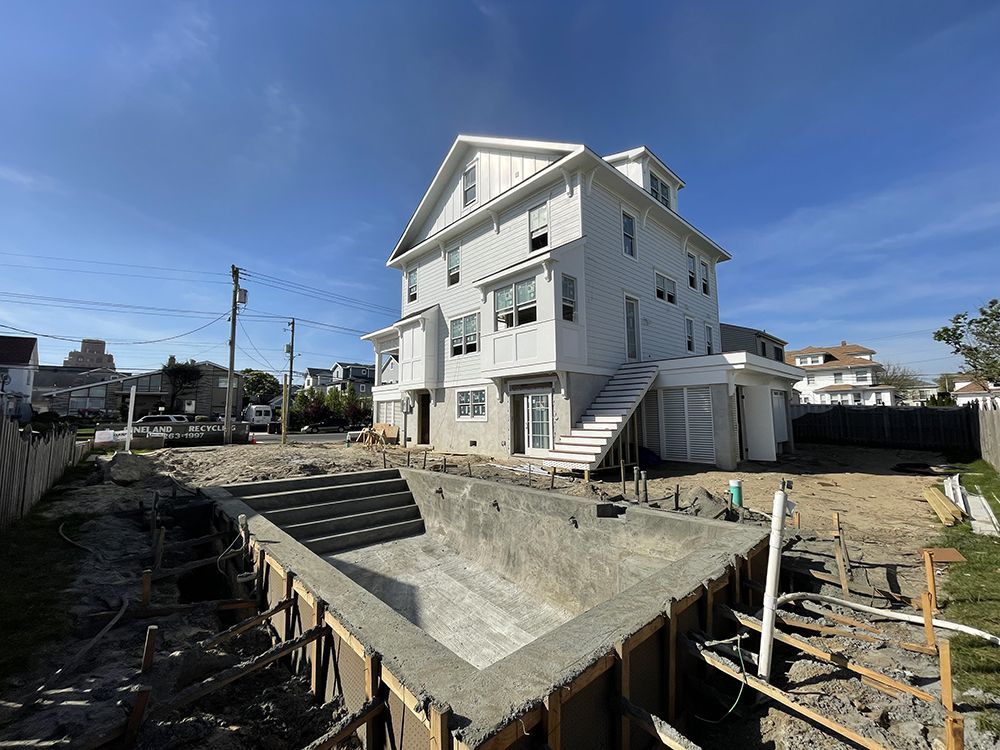 A large white house is being built with a swimming pool in the backyard.