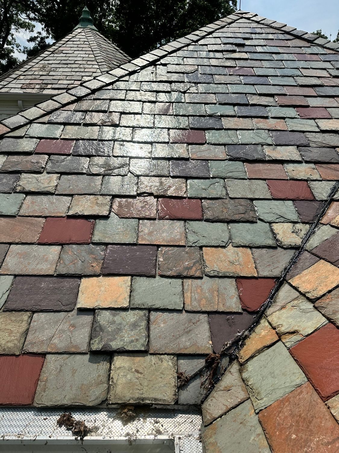 Multicolored slate roof tiles with a ridge line and a valley seam, seen close up