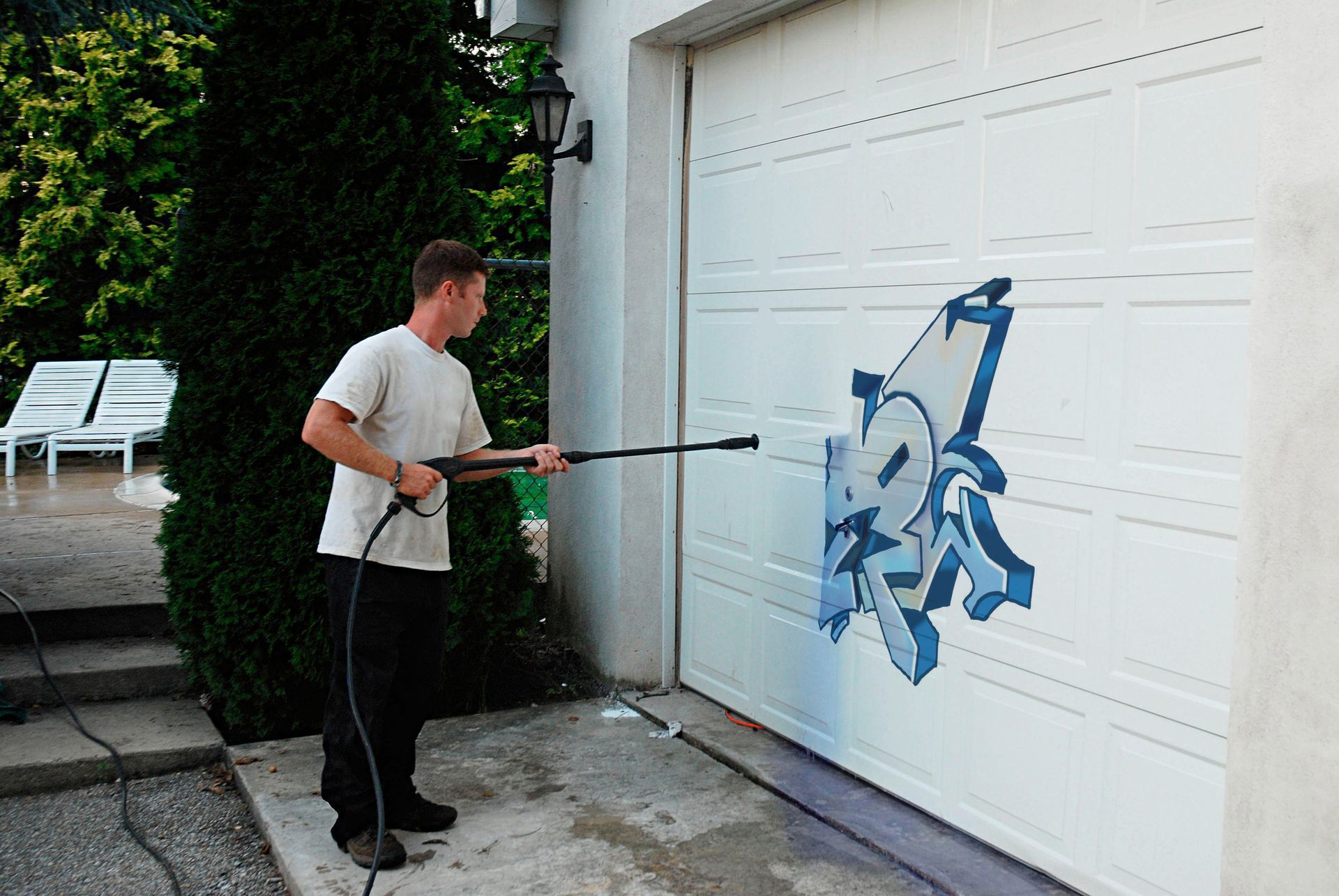 Person spray-painting graffiti on a white garage door outdoors