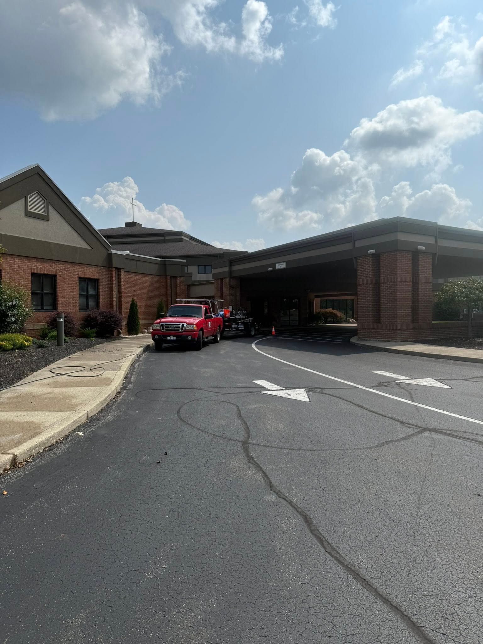 Red fire truck parked at a brick building entrance under a cloudy sky