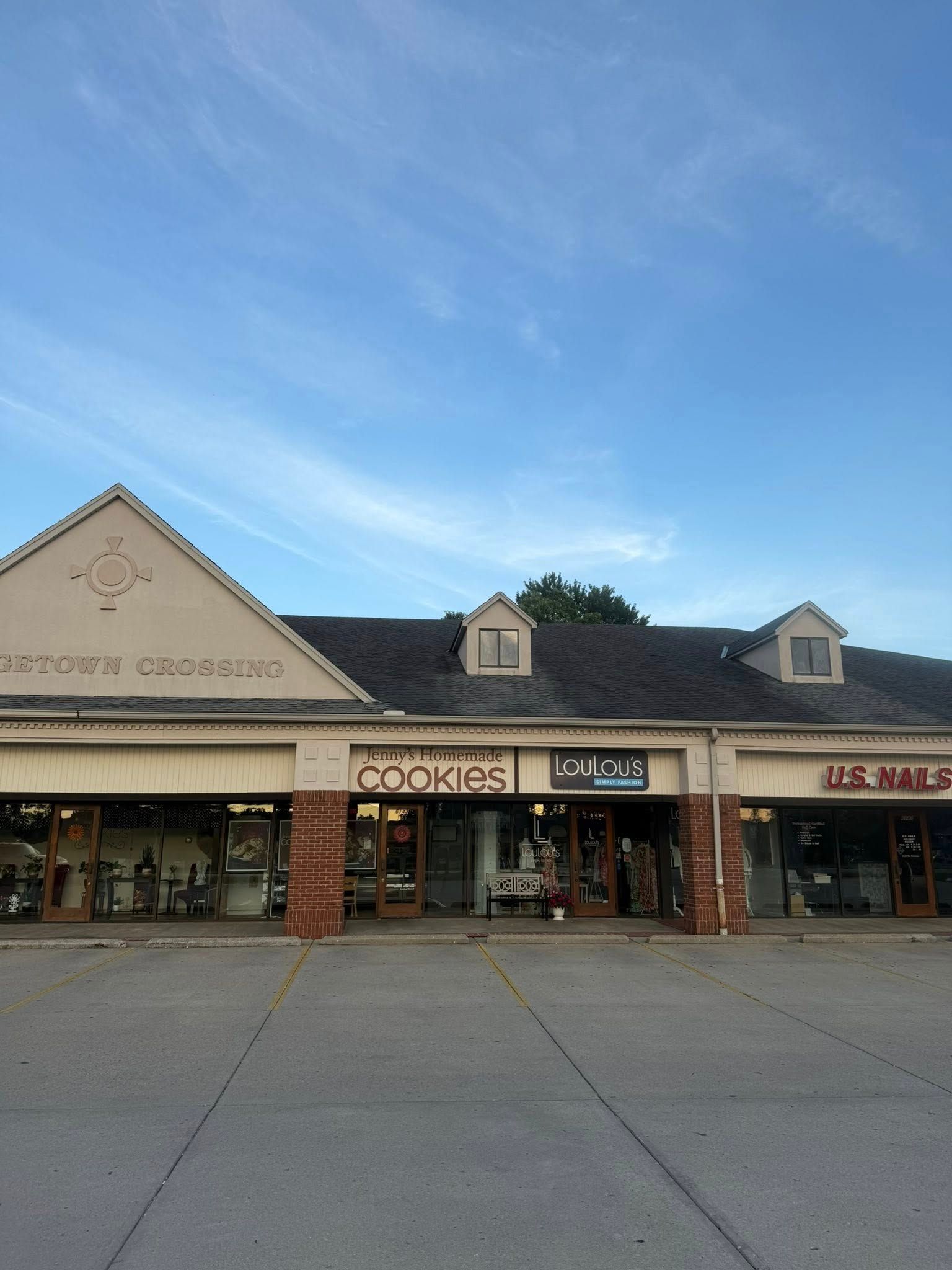 Strip mall storefronts with a Cookies shop and blue sky overhead
