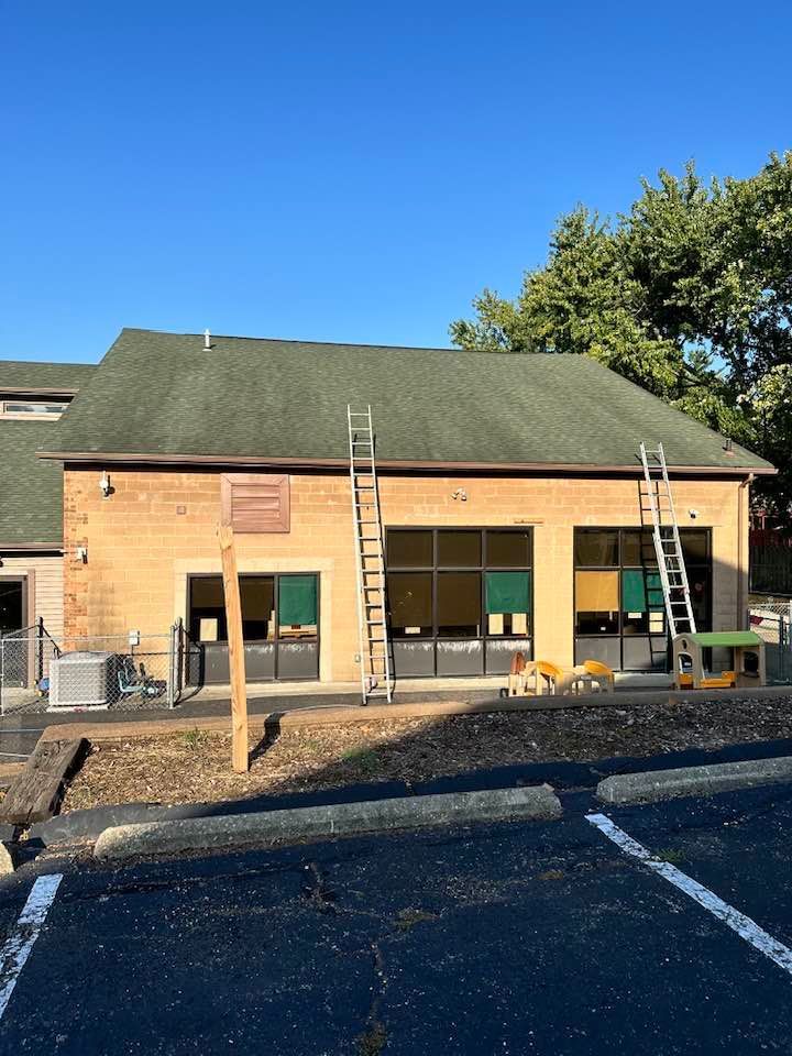 Brick building with green roof and two ladders outside on a sunny day