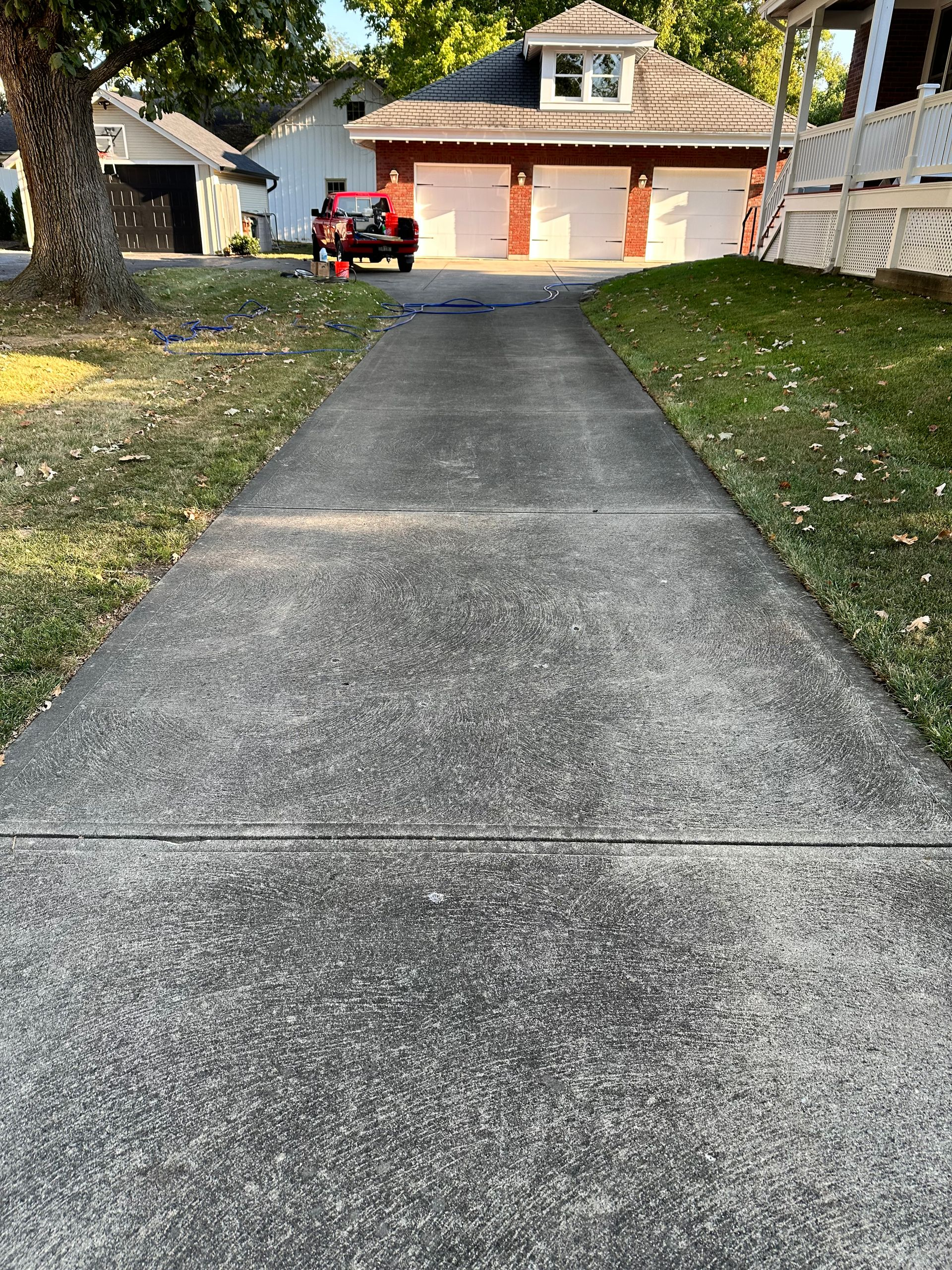 Long driveway leading to a house with a garage and a red vehicle parked outside.