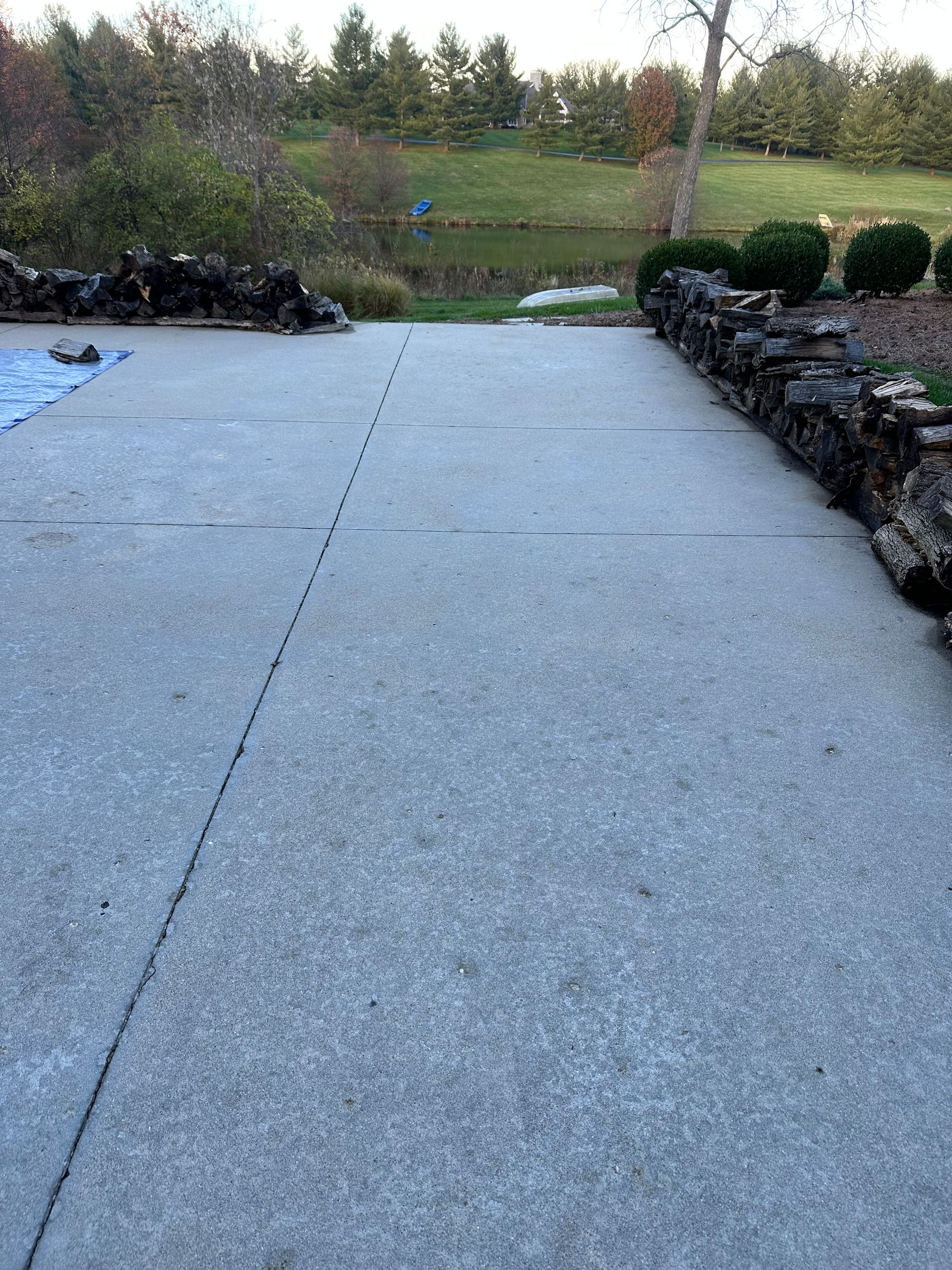 Snow-dusted patio with stone walls, leading to a grassy field and trees beyond.