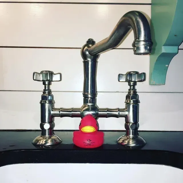 Chrome bathroom faucet with two handles and a red rubber duck under the spout