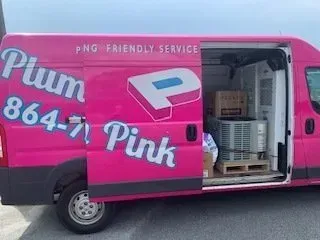 Pink delivery van with open side door, “Plum Pink” branding, and stacked white containers inside