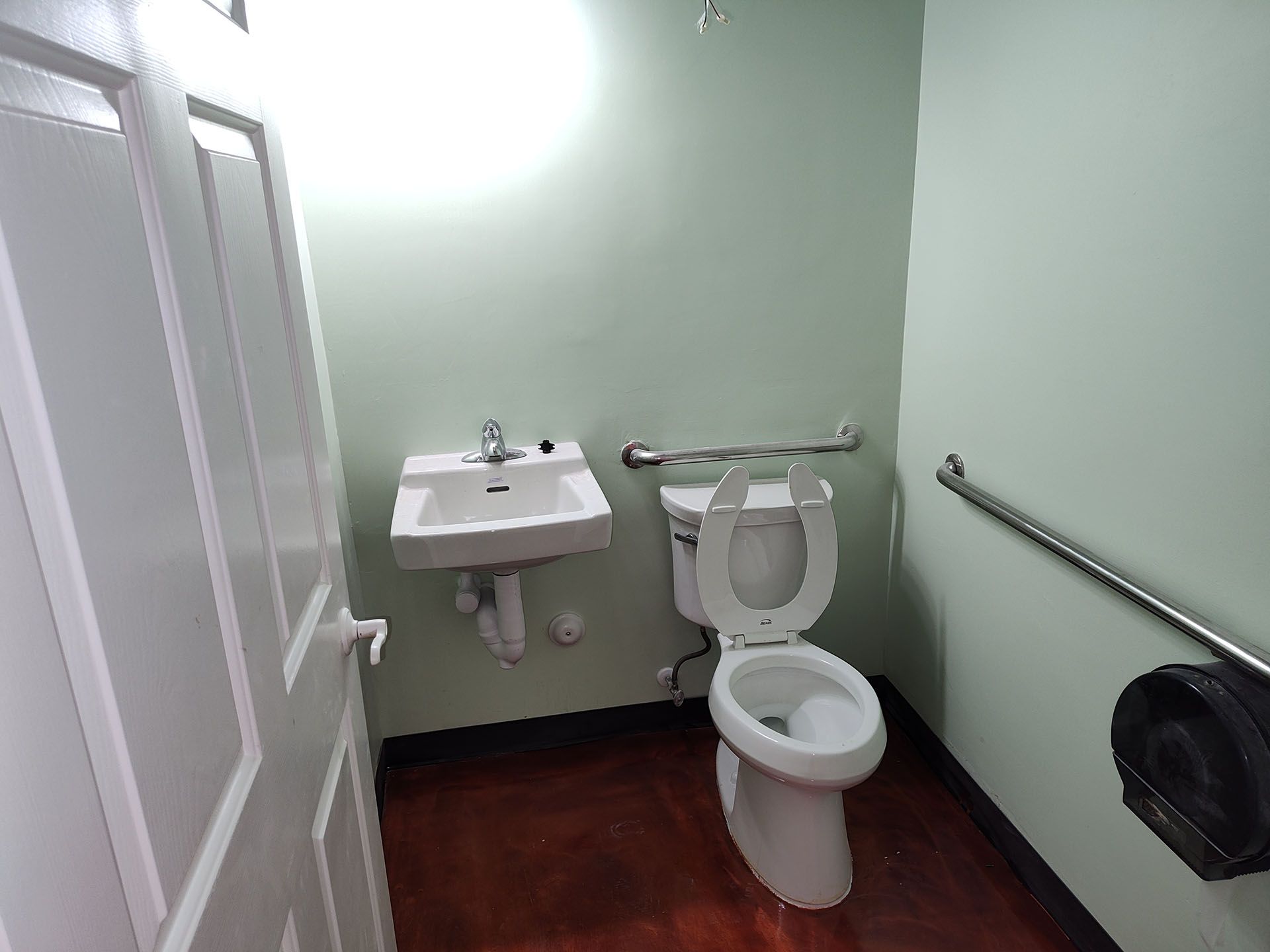 A bathroom with a toilet , sink and handrails