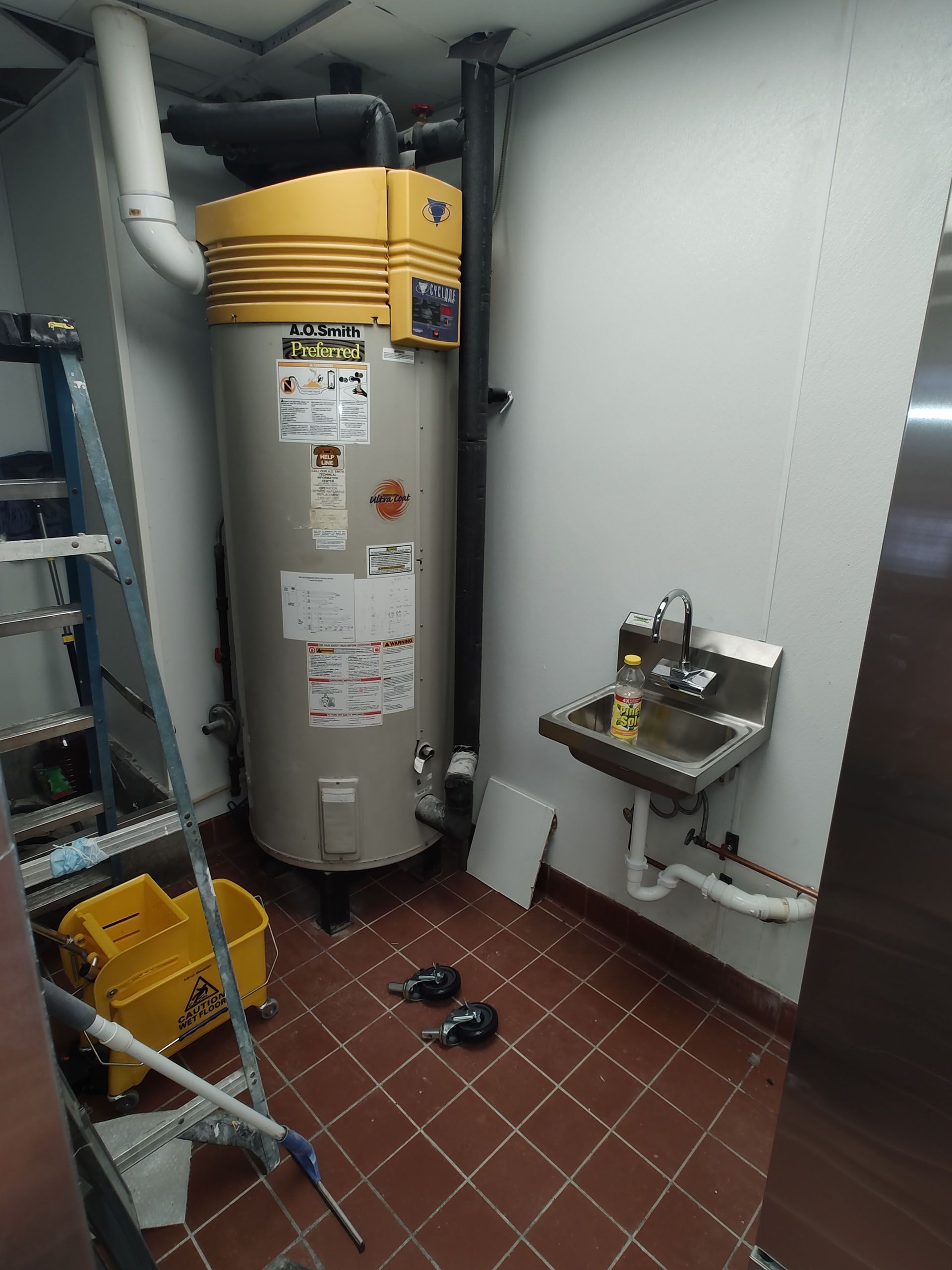 A water heater is sitting in a room next to a sink.
