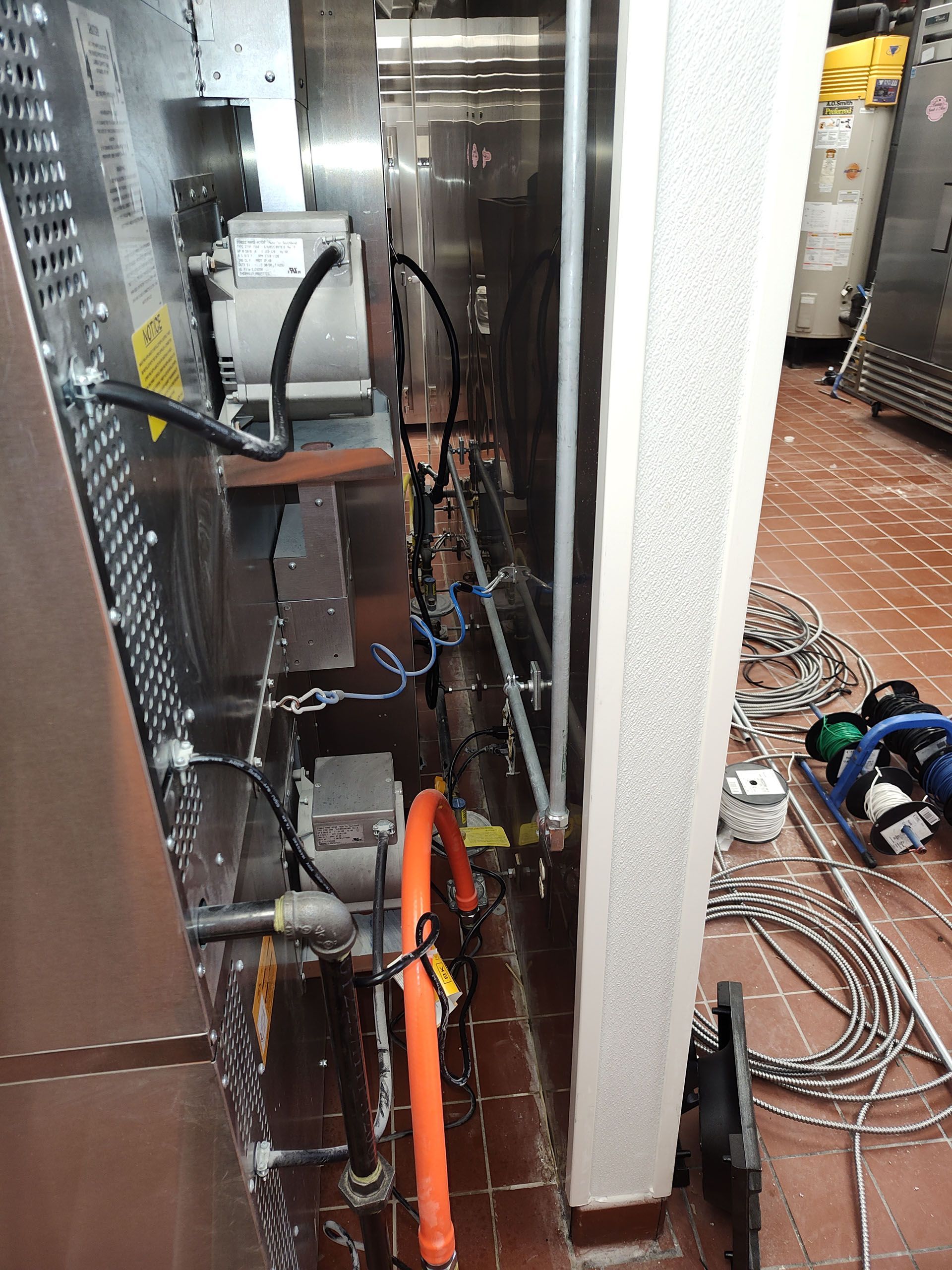 A stainless steel oven is being repaired in a kitchen.