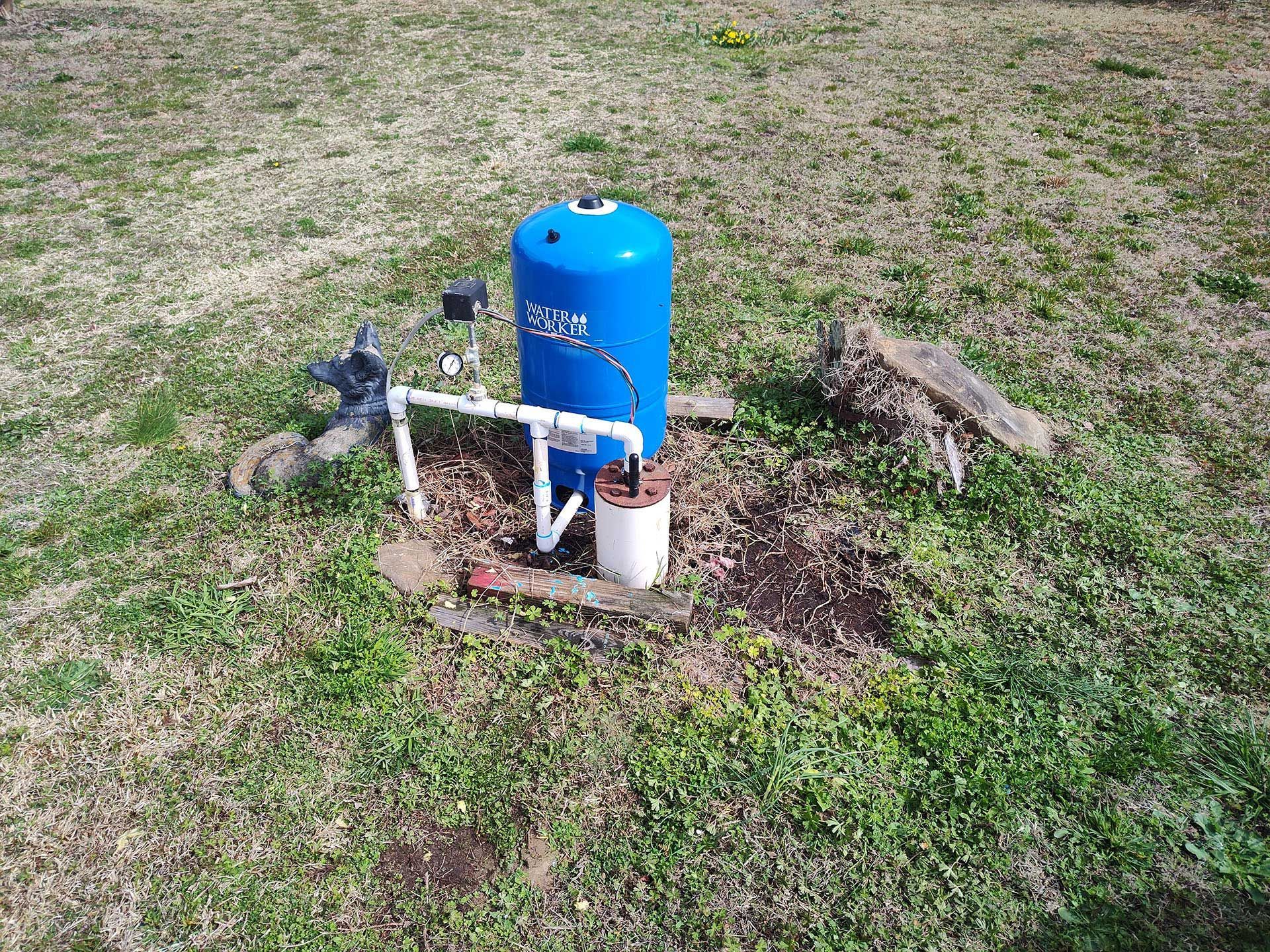 A blue water tank is sitting in the middle of a grassy field.