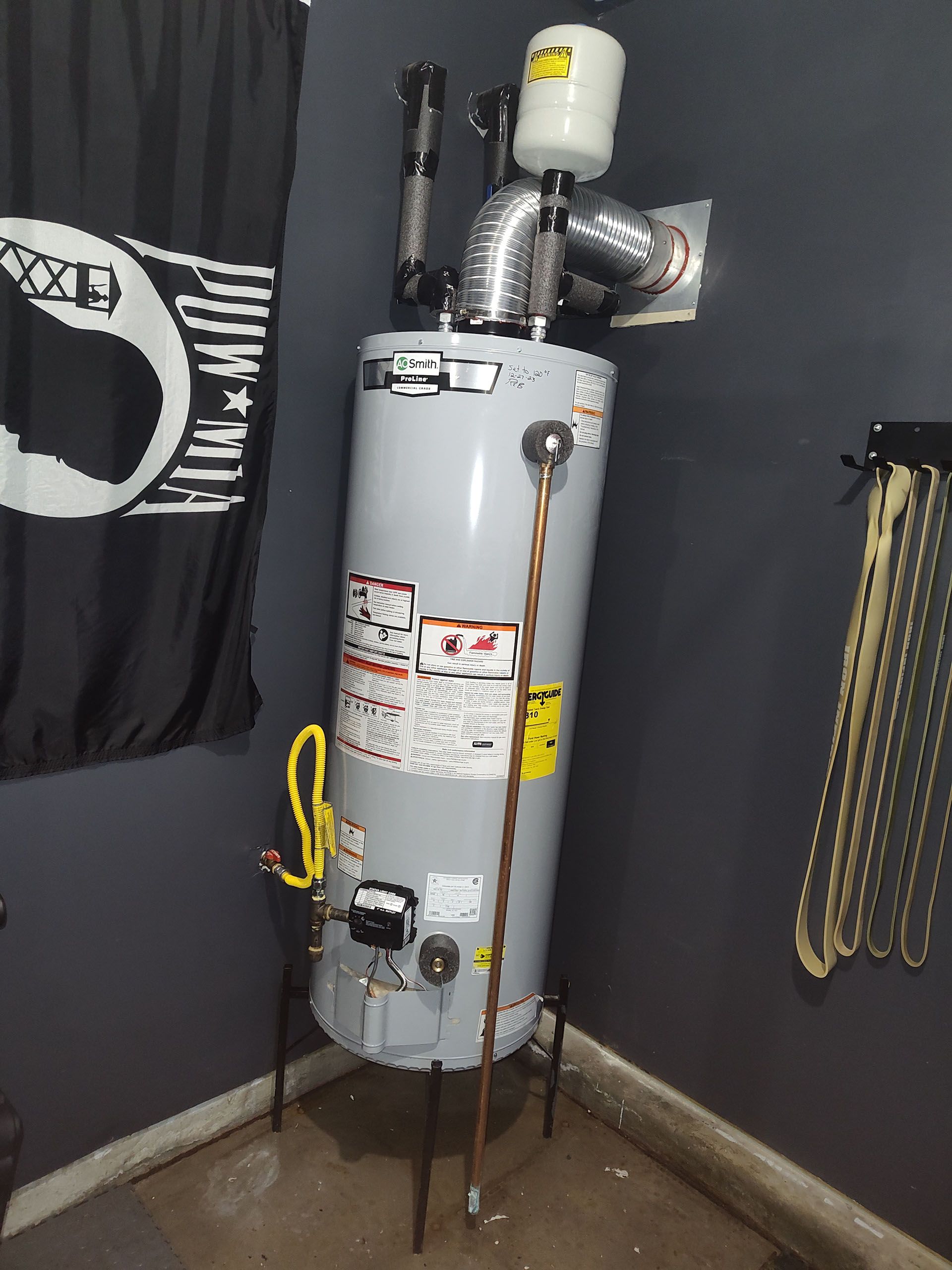 A water heater is sitting in a room next to a black flag.