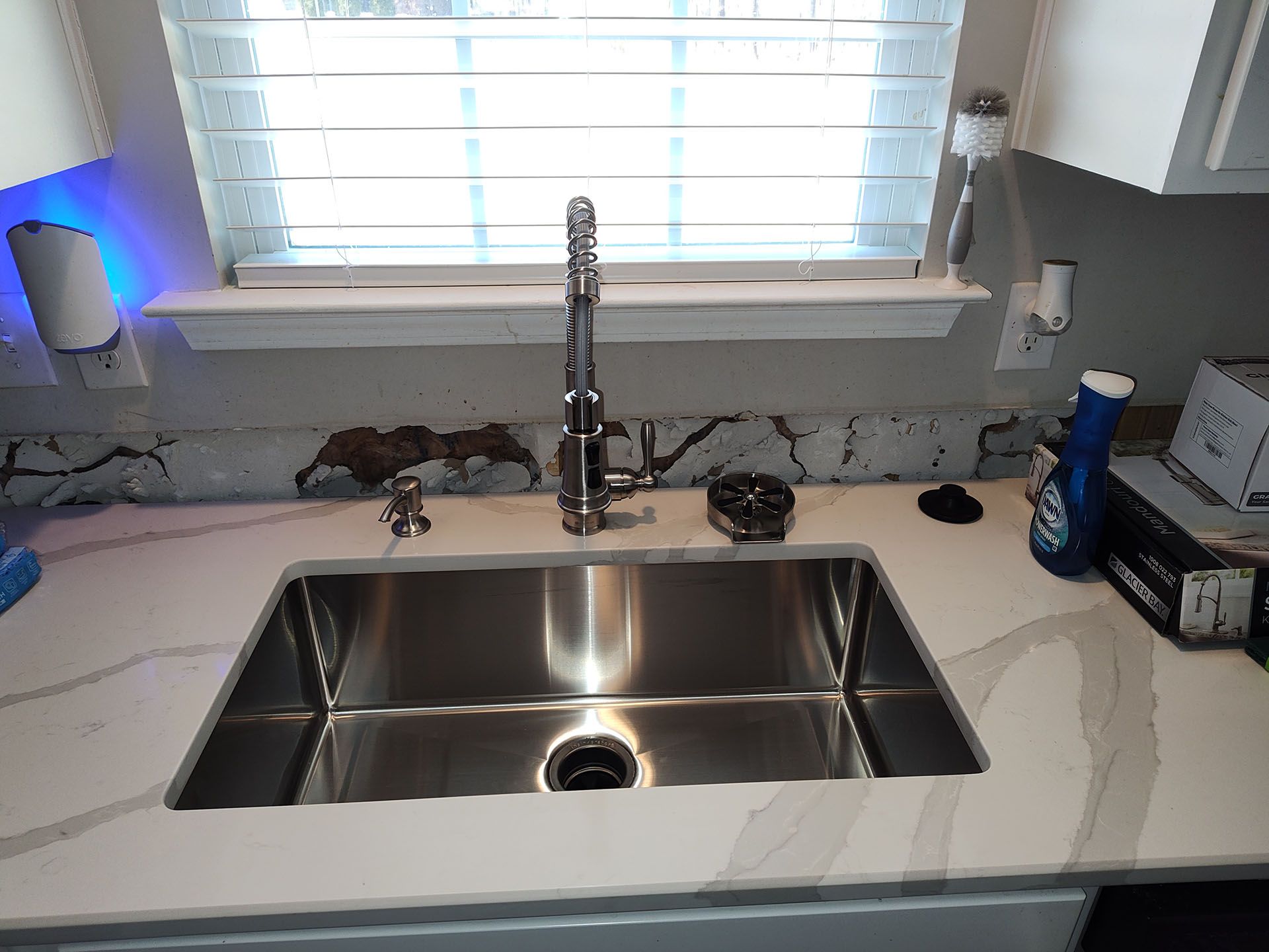 A kitchen sink with a faucet and a window in the background.