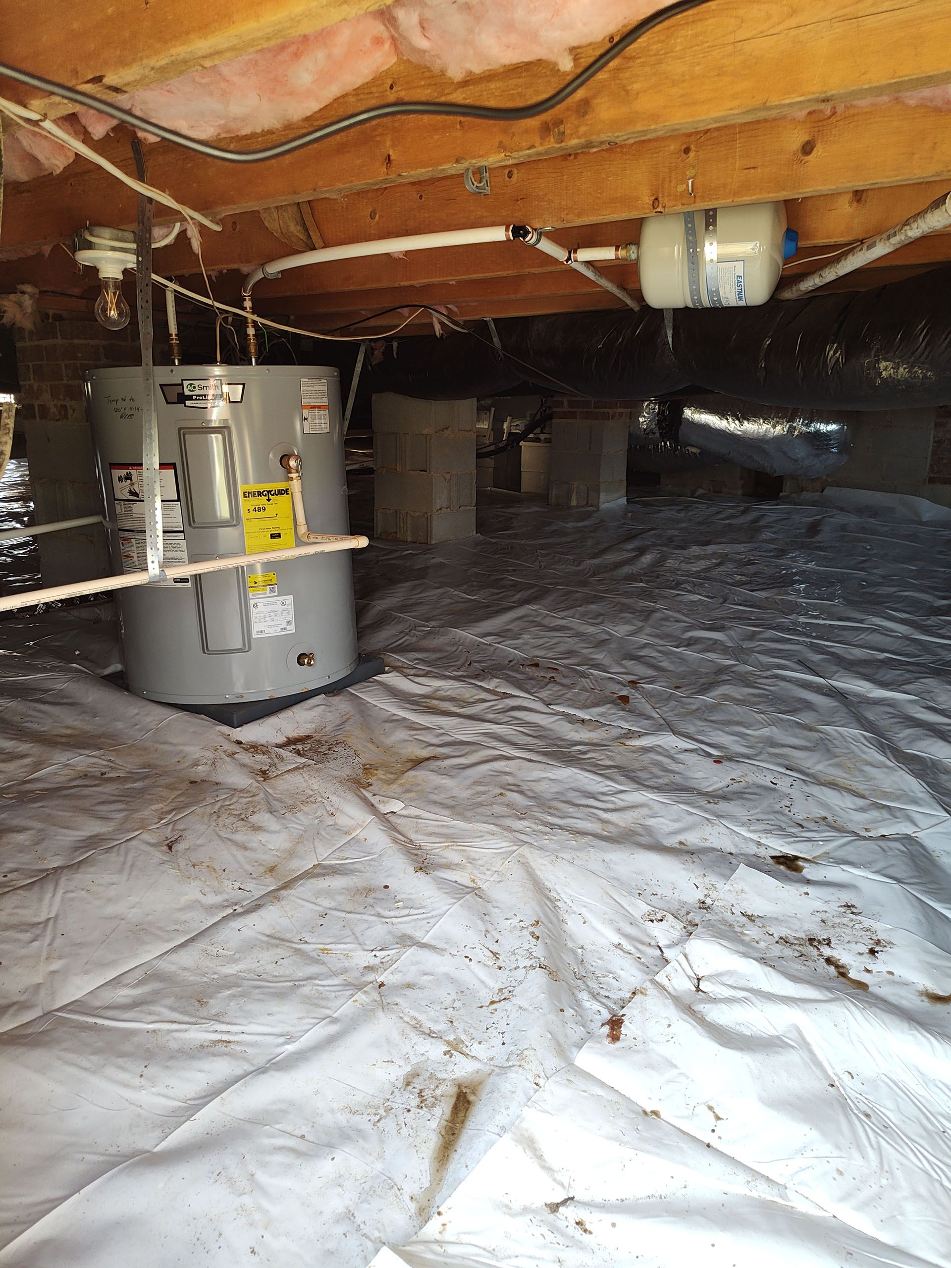 A water heater is sitting in the crawl space of a house.