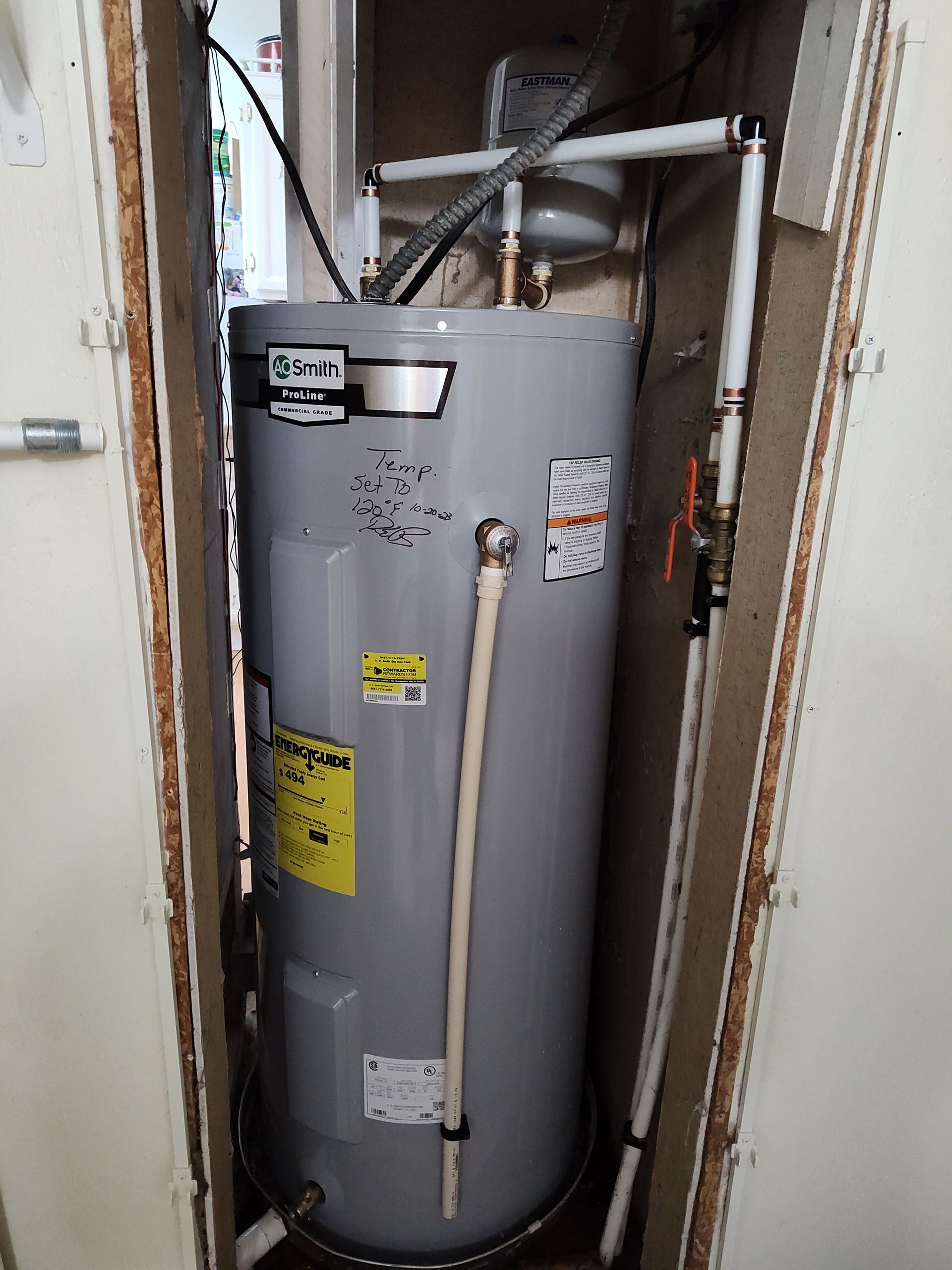 A gray water heater is sitting in a corner of a room.