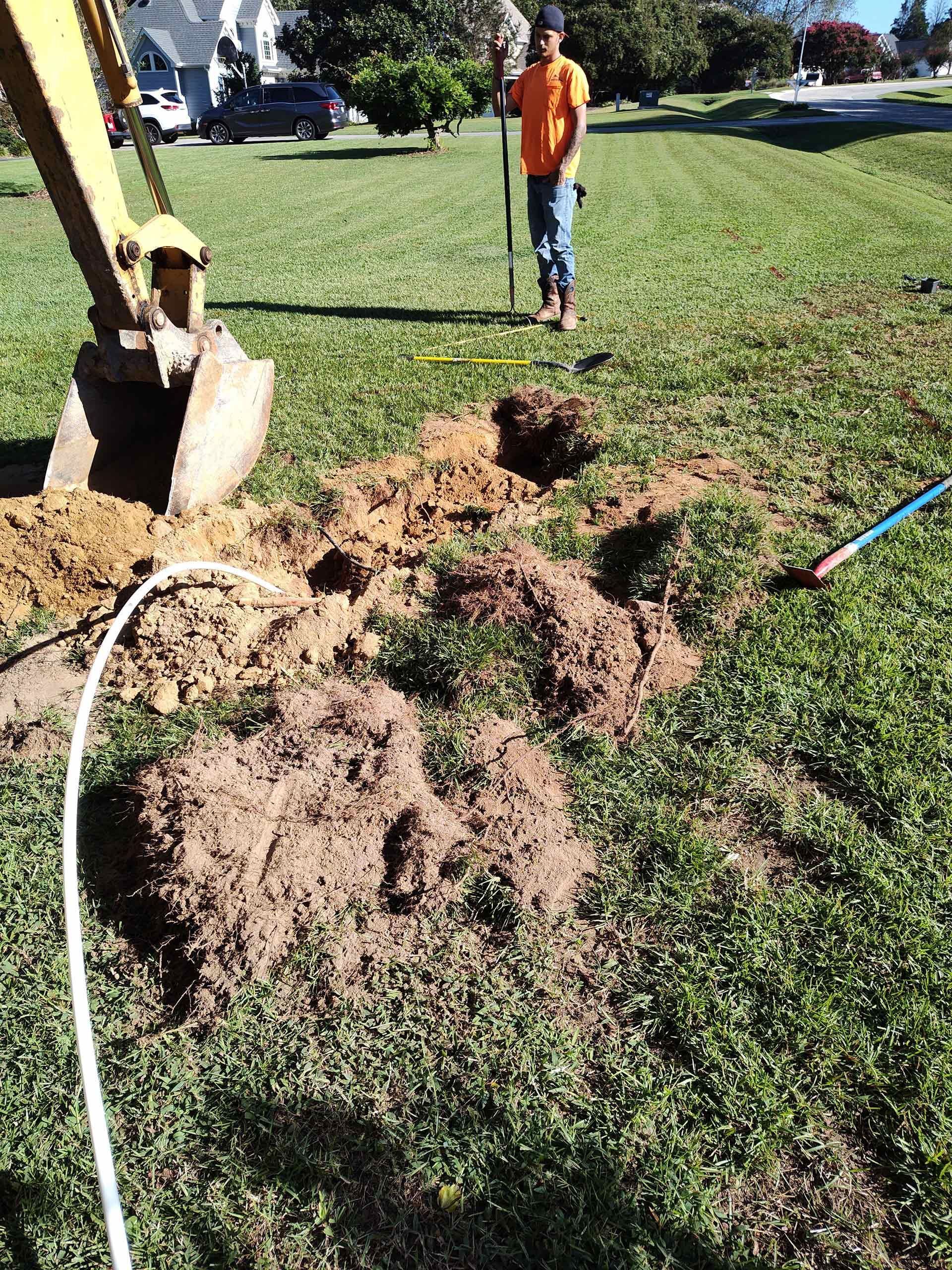 A man is digging a hole in the grass with a shovel.