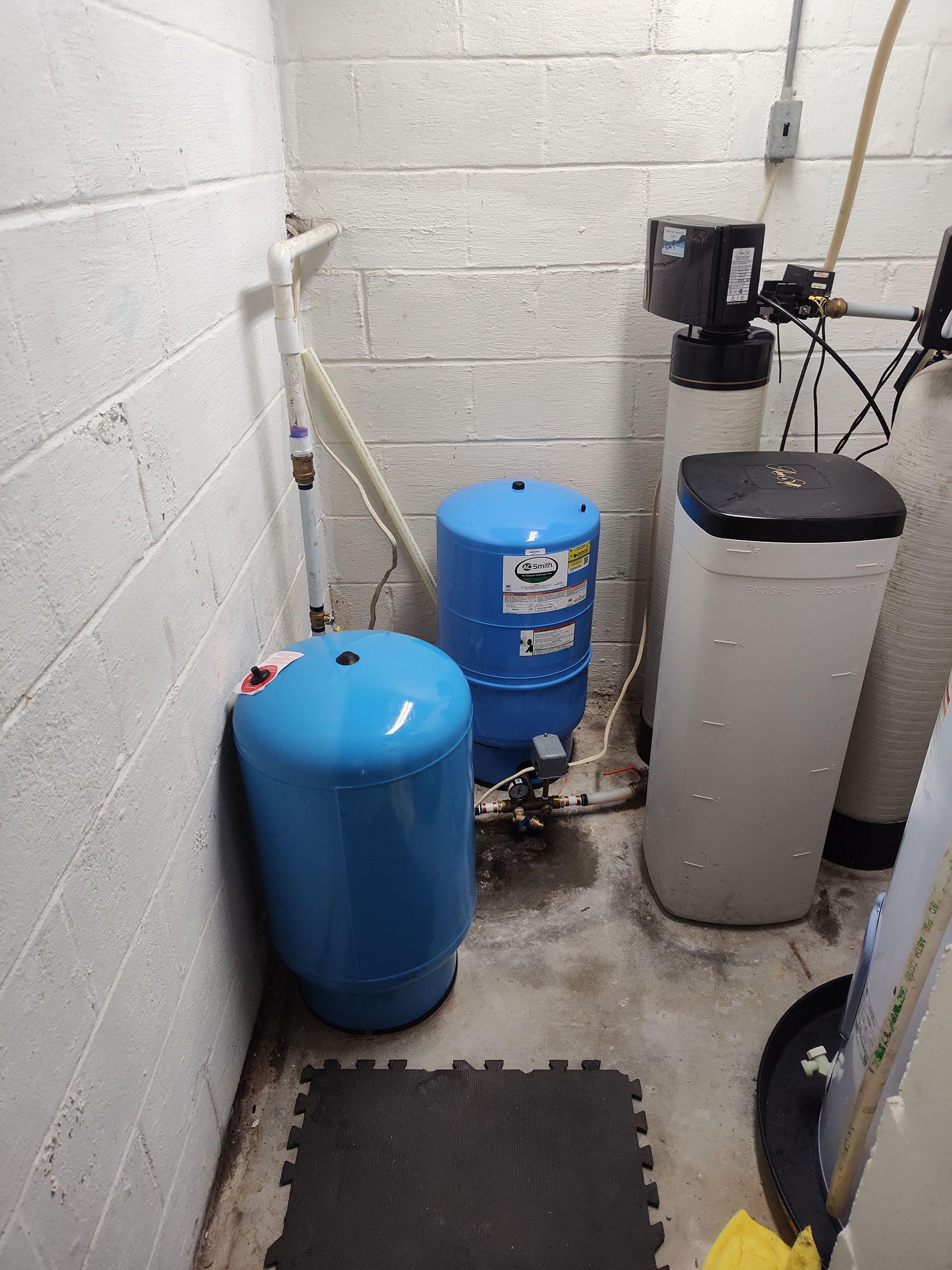 A room with two blue tanks and a water softener.