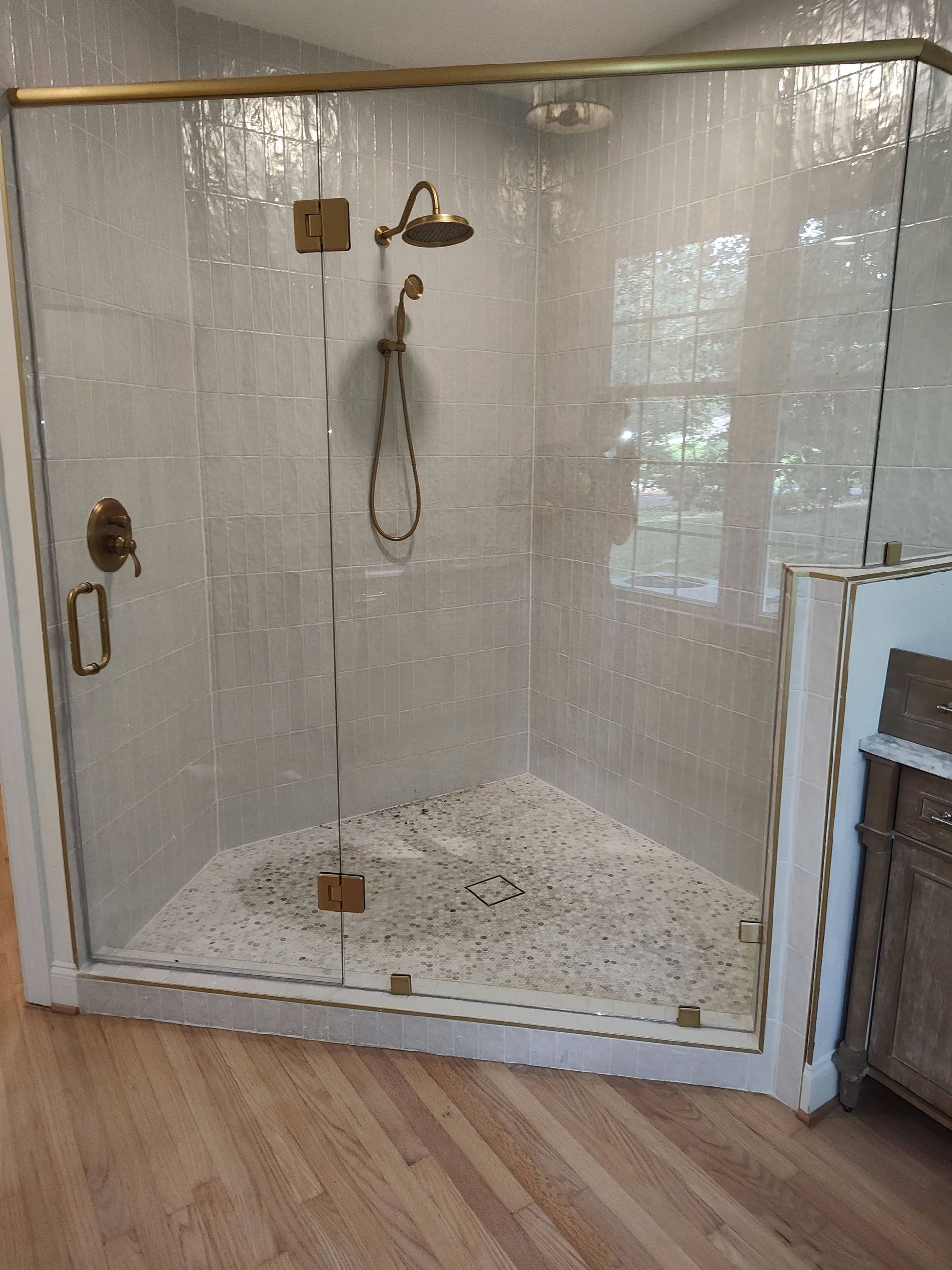 A bathroom with a walk in shower with a glass door.