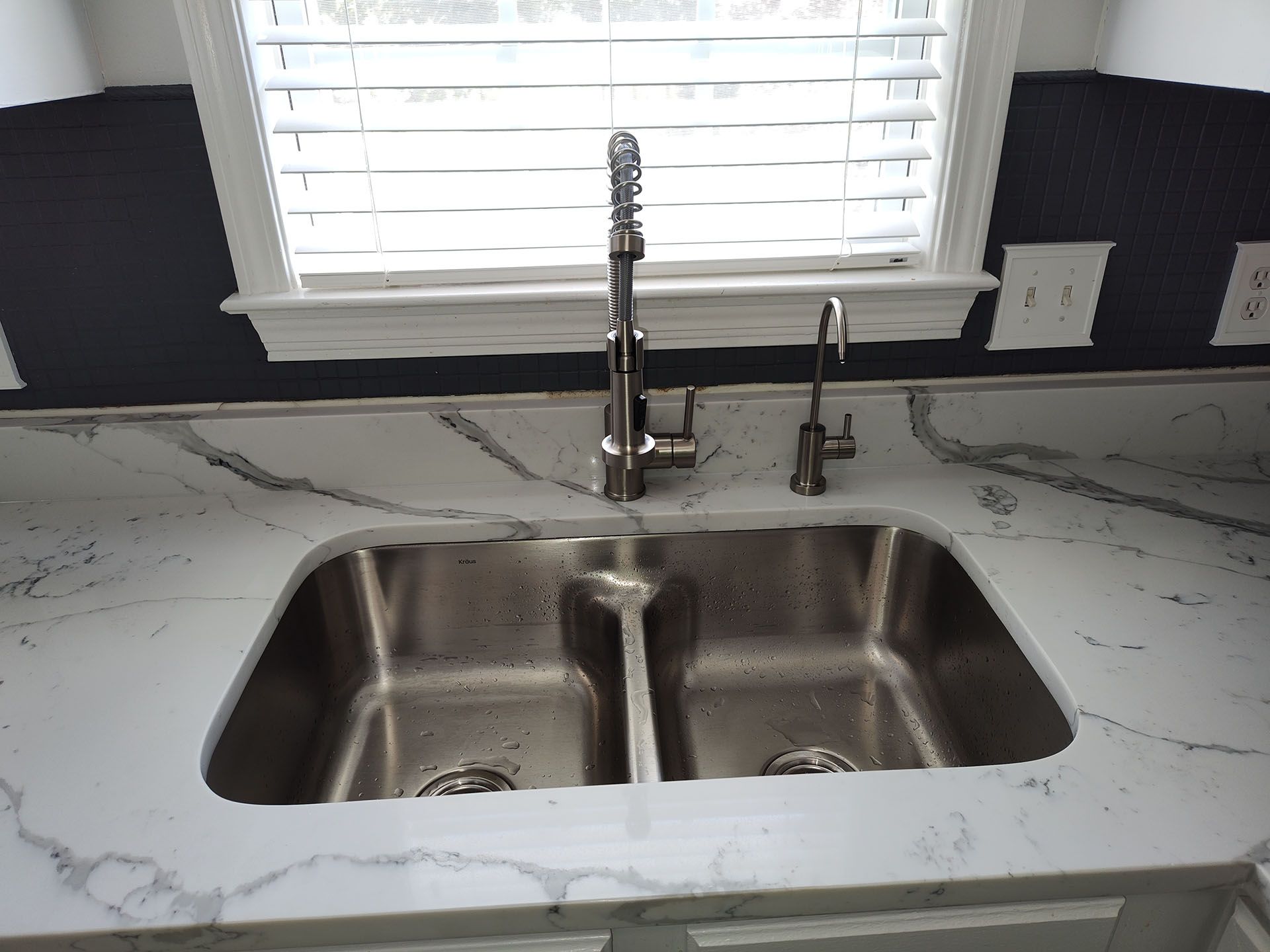 A kitchen sink with two stainless steel sinks and a faucet.