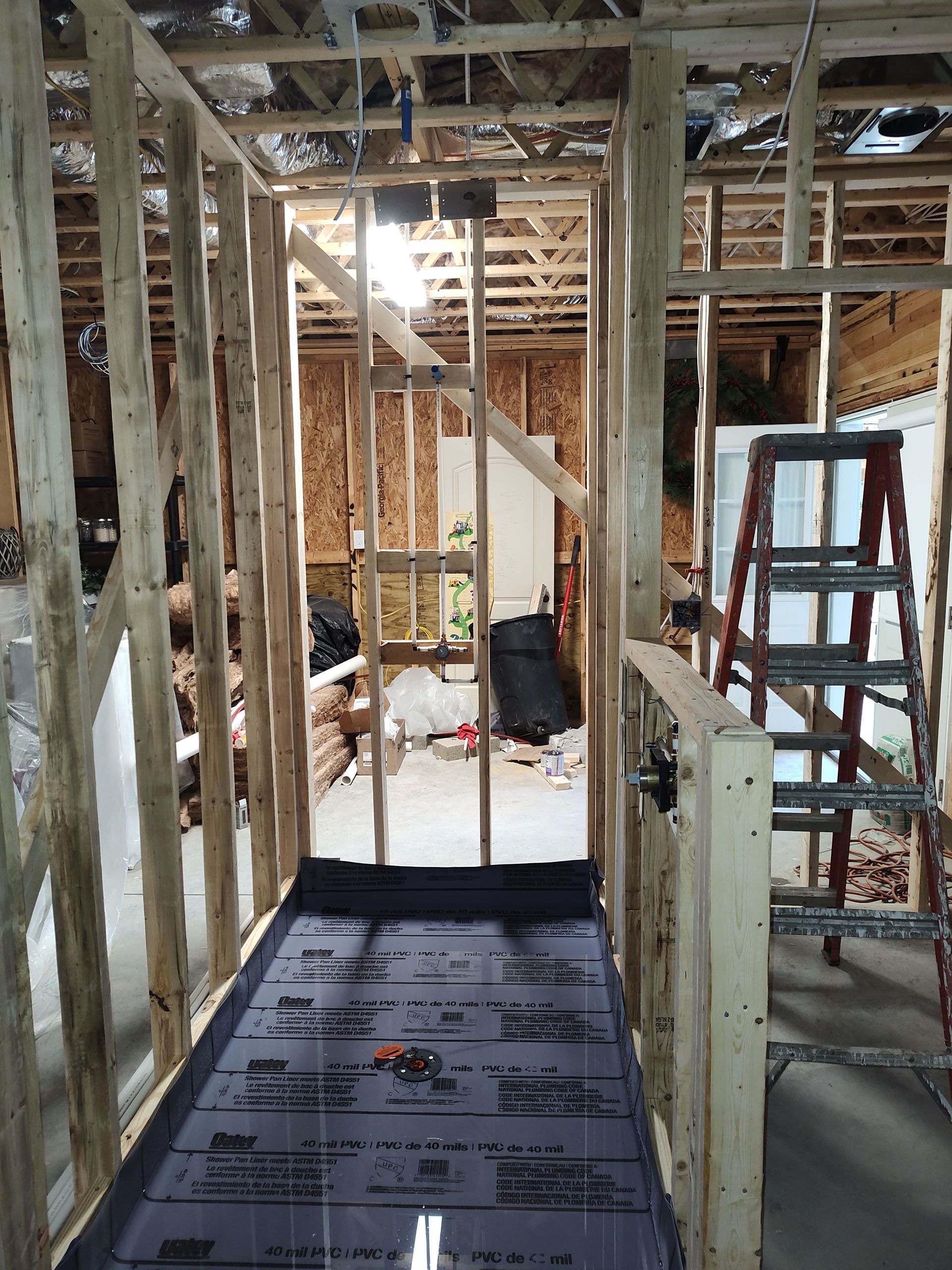 A hallway in a house under construction with a ladder in the background.