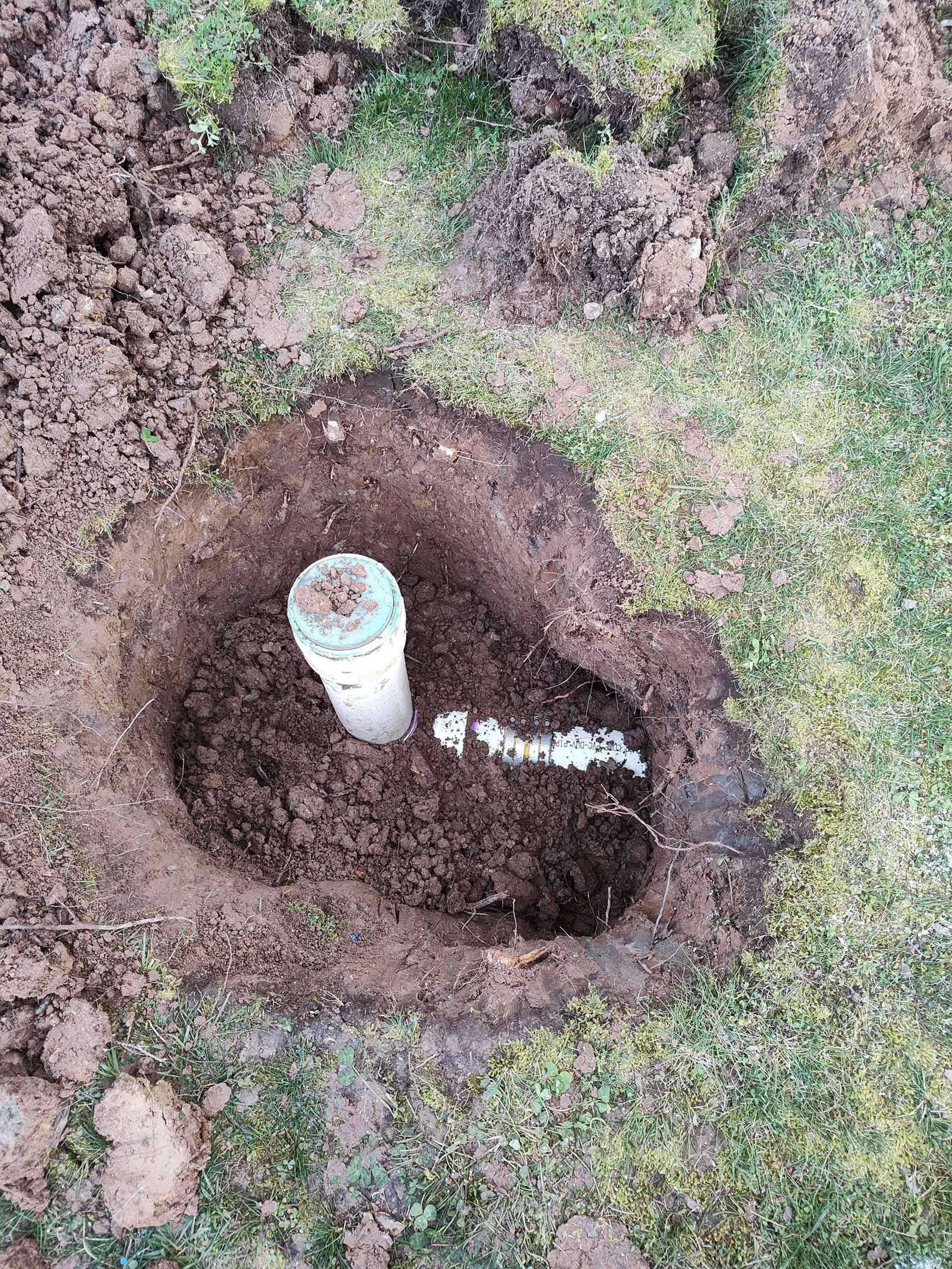 A hole in the ground with a pipe in it.