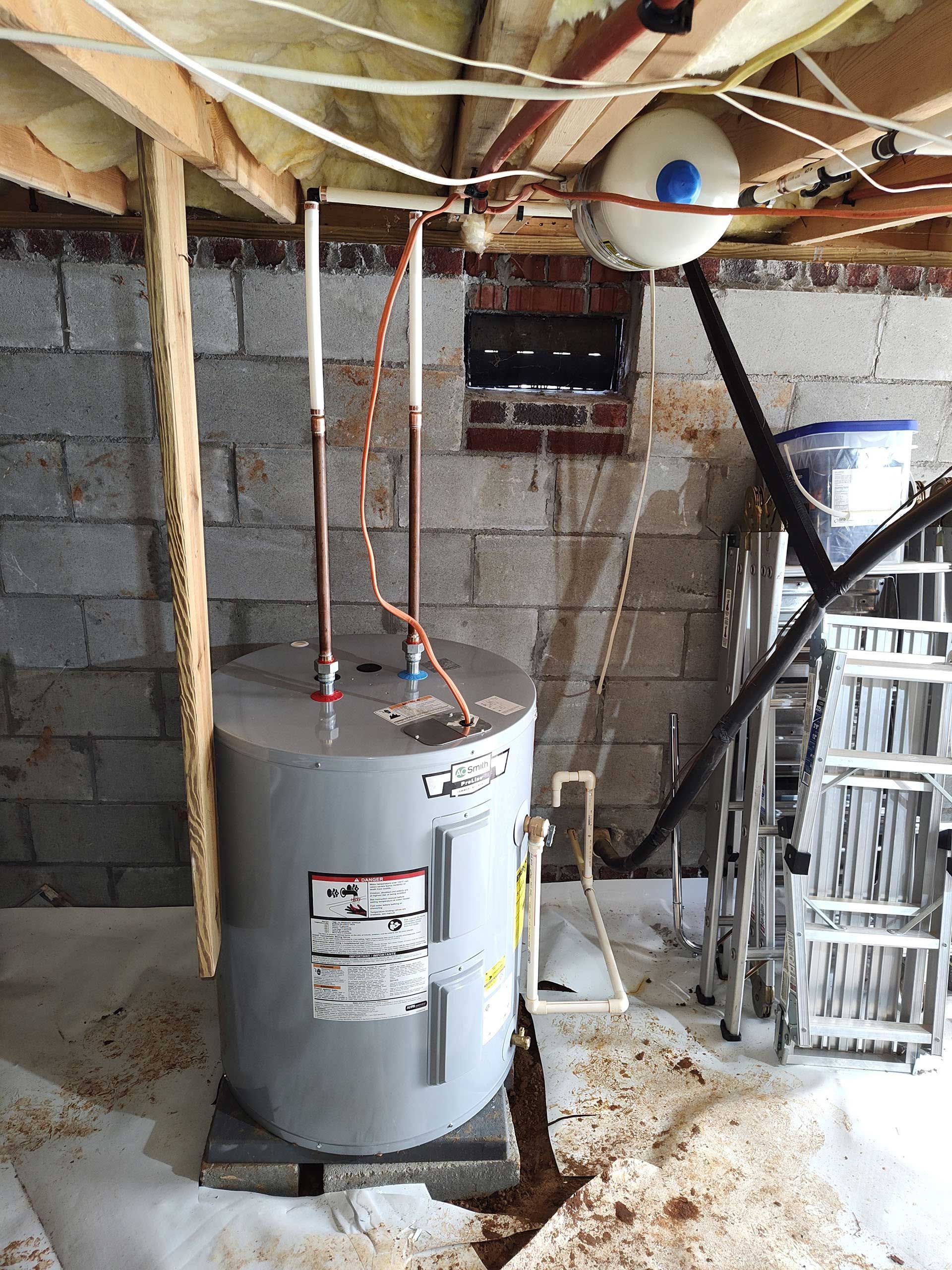 A water heater is sitting in a basement next to a ladder.