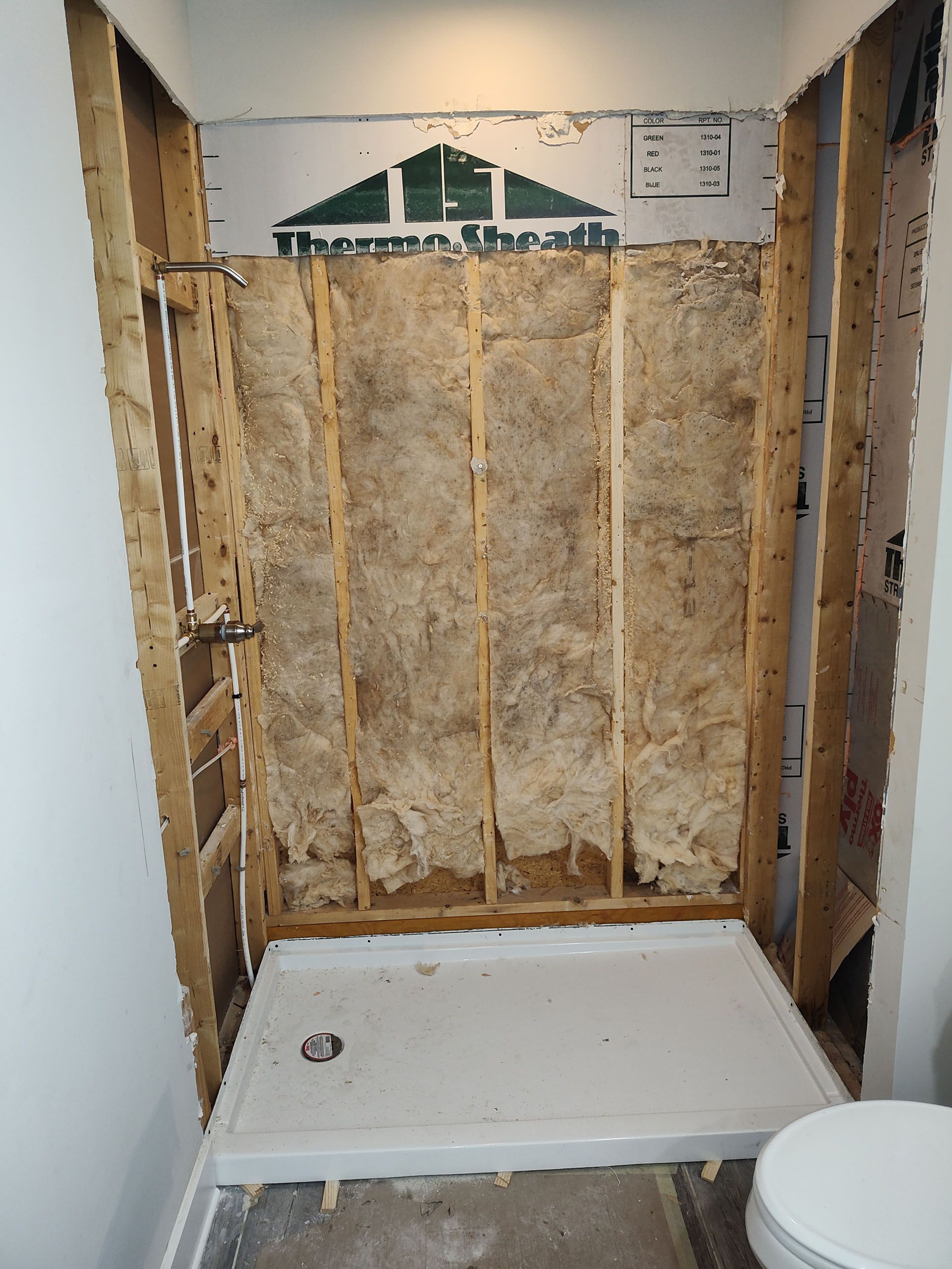 A bathroom with a toilet and a shower stall under construction.